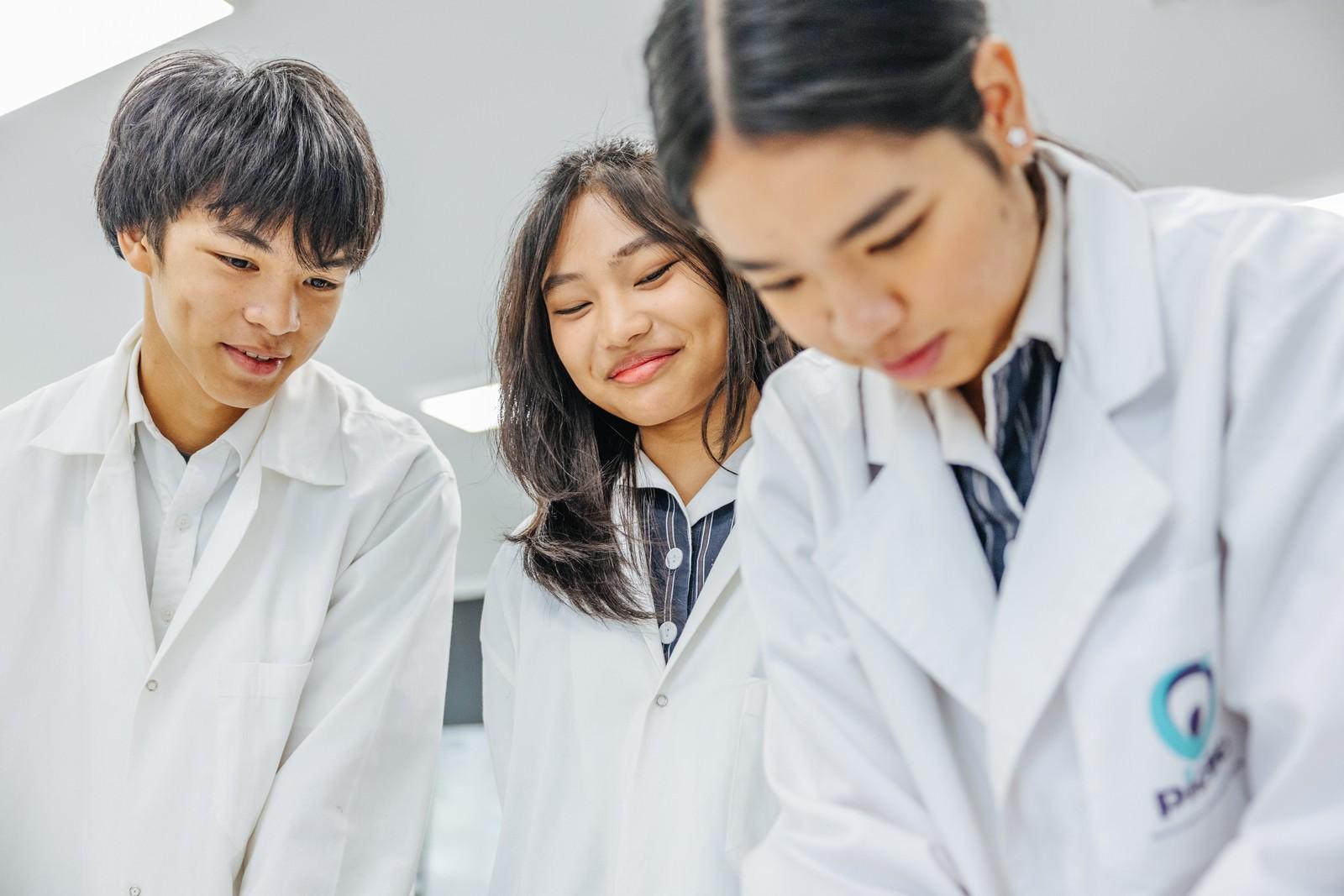 Secondary students in Hobart TAS work together on a science experiment in lab coats