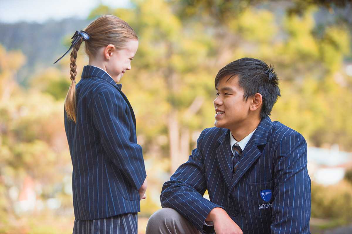High school kneeling and listenting to year 1 student wearing ACC Hobart uniform