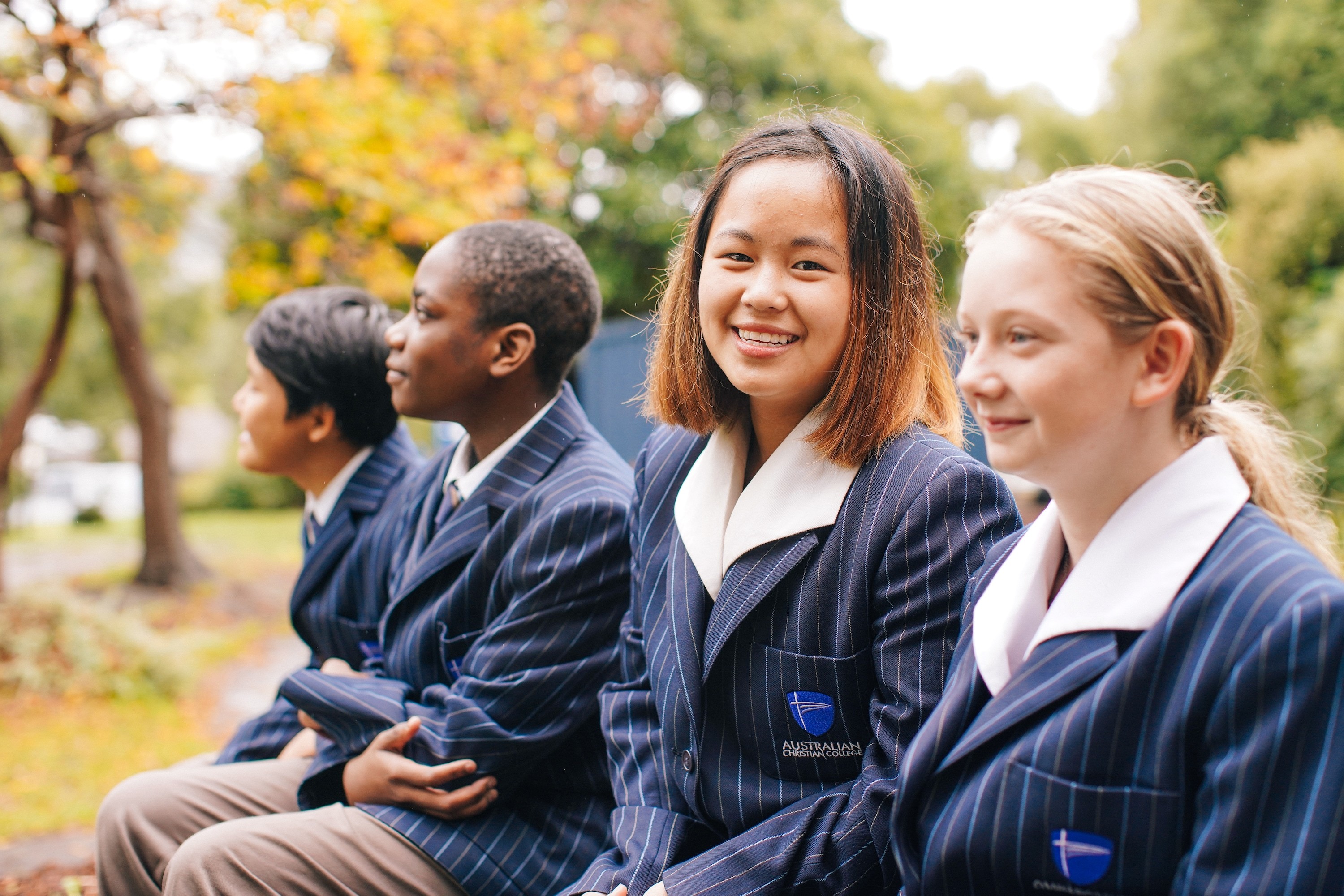 Groupd of Hobart school students sitting together on bench smiling