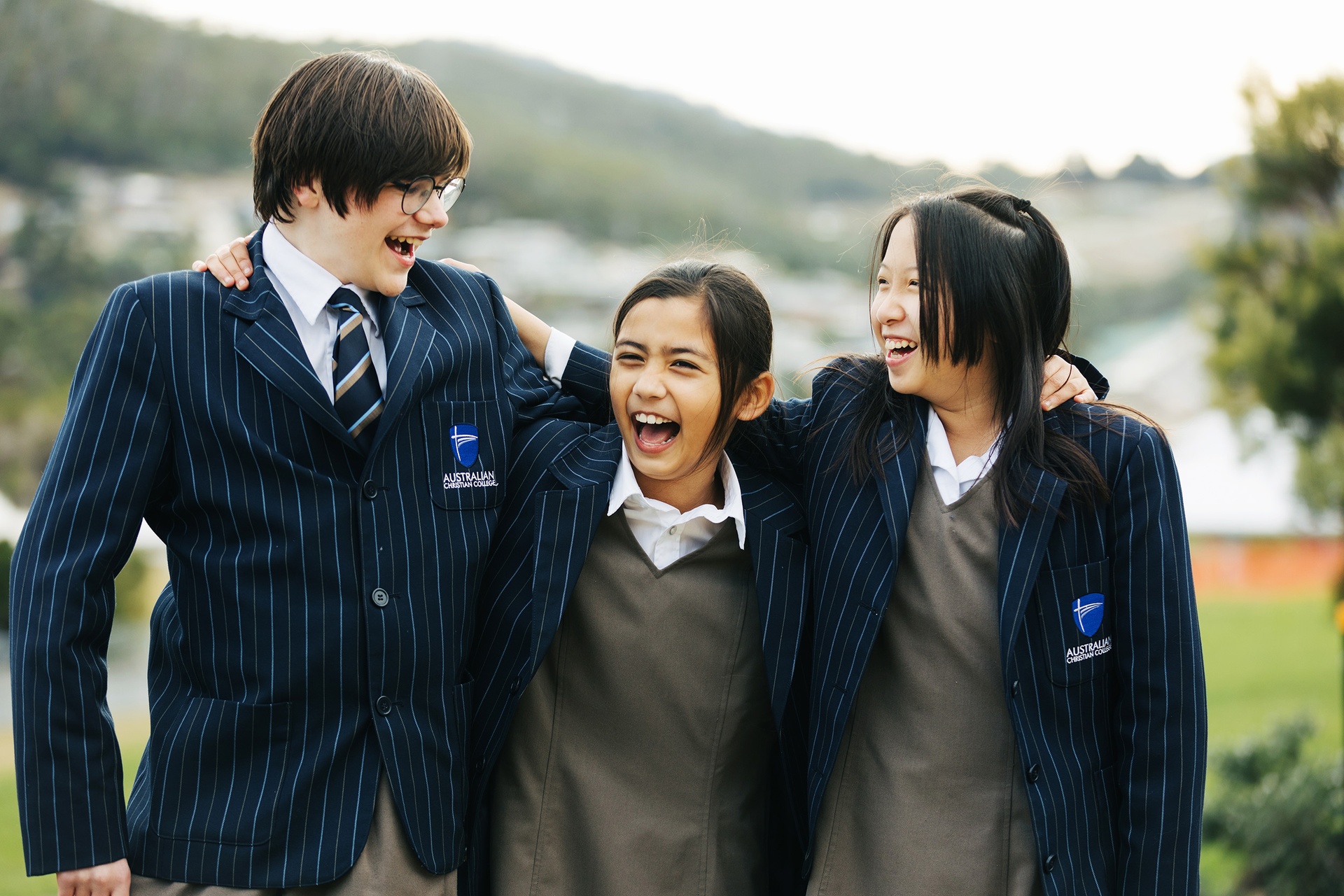 ACC Hume students wearing formal winter uniform laughing together with arms around one another