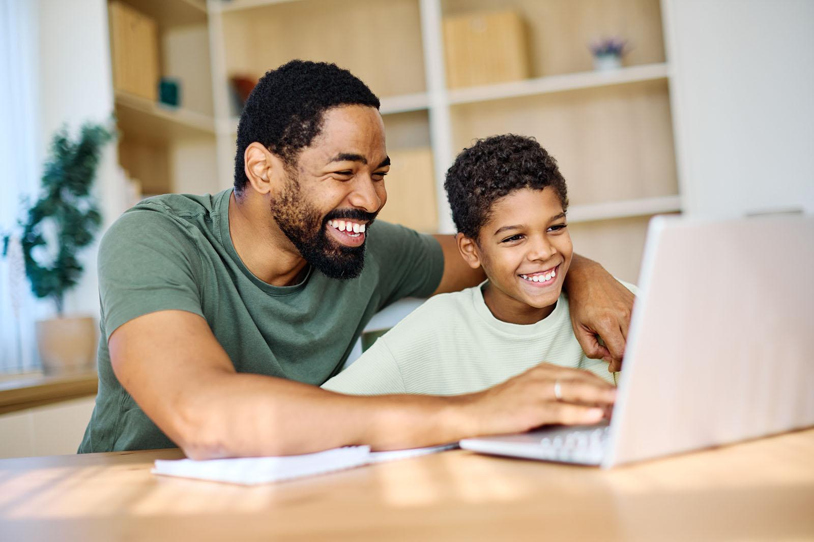 Parent assisting child with learning on a laptop at home
