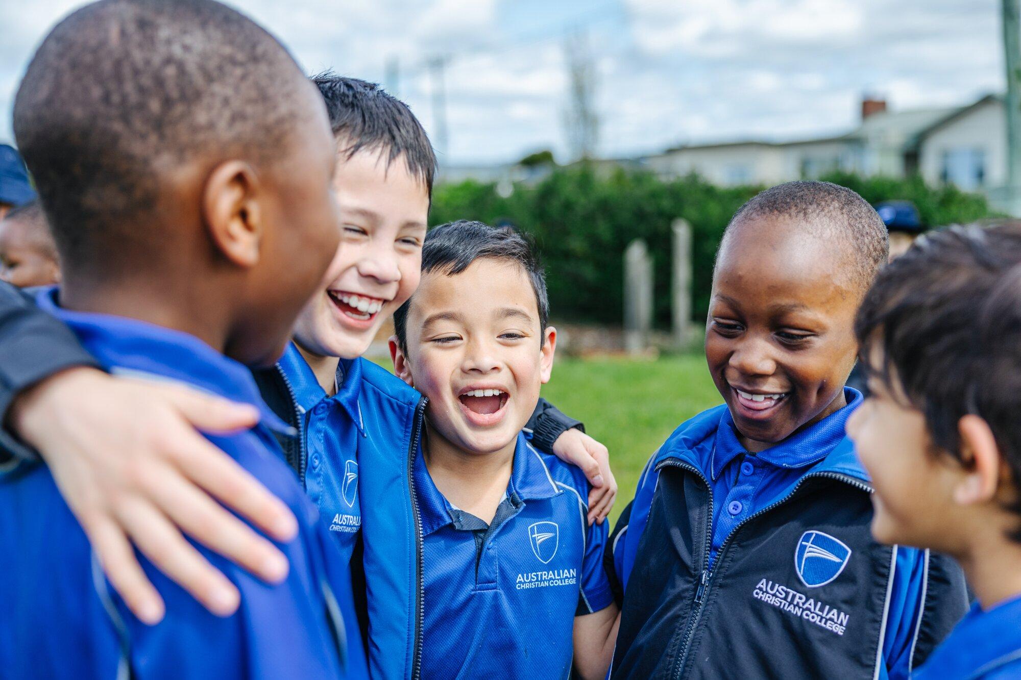 Primary boys in ACC uniform laughing together outdoors at Launceston