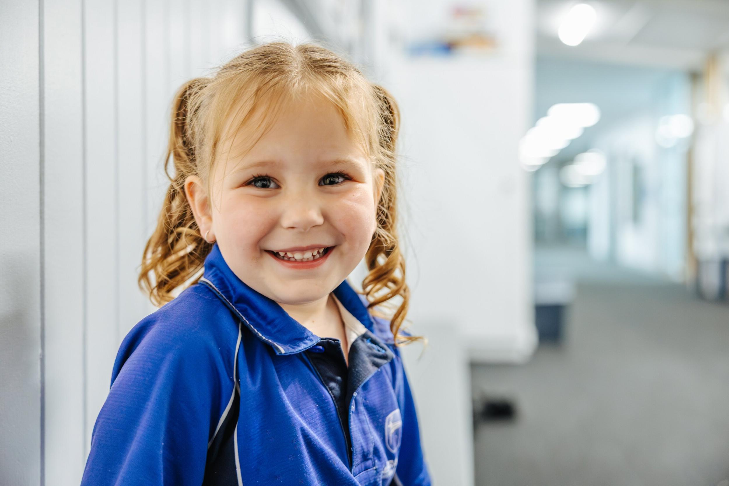 Primary girl smiling in the school hallway at ACC Launceston