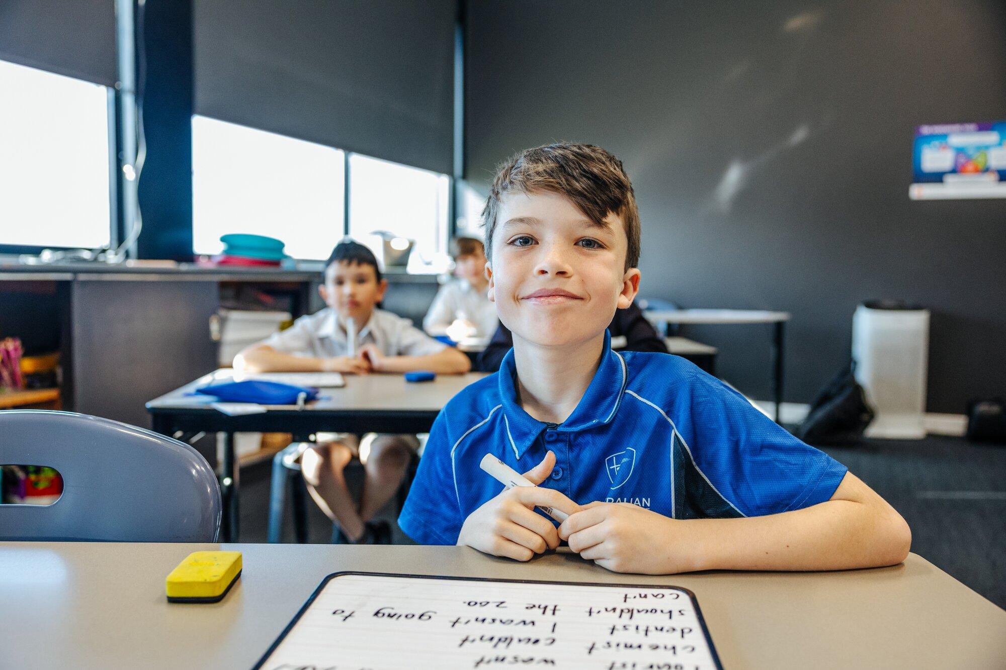 Primary student practising spelling on a whiteboard at Launceston