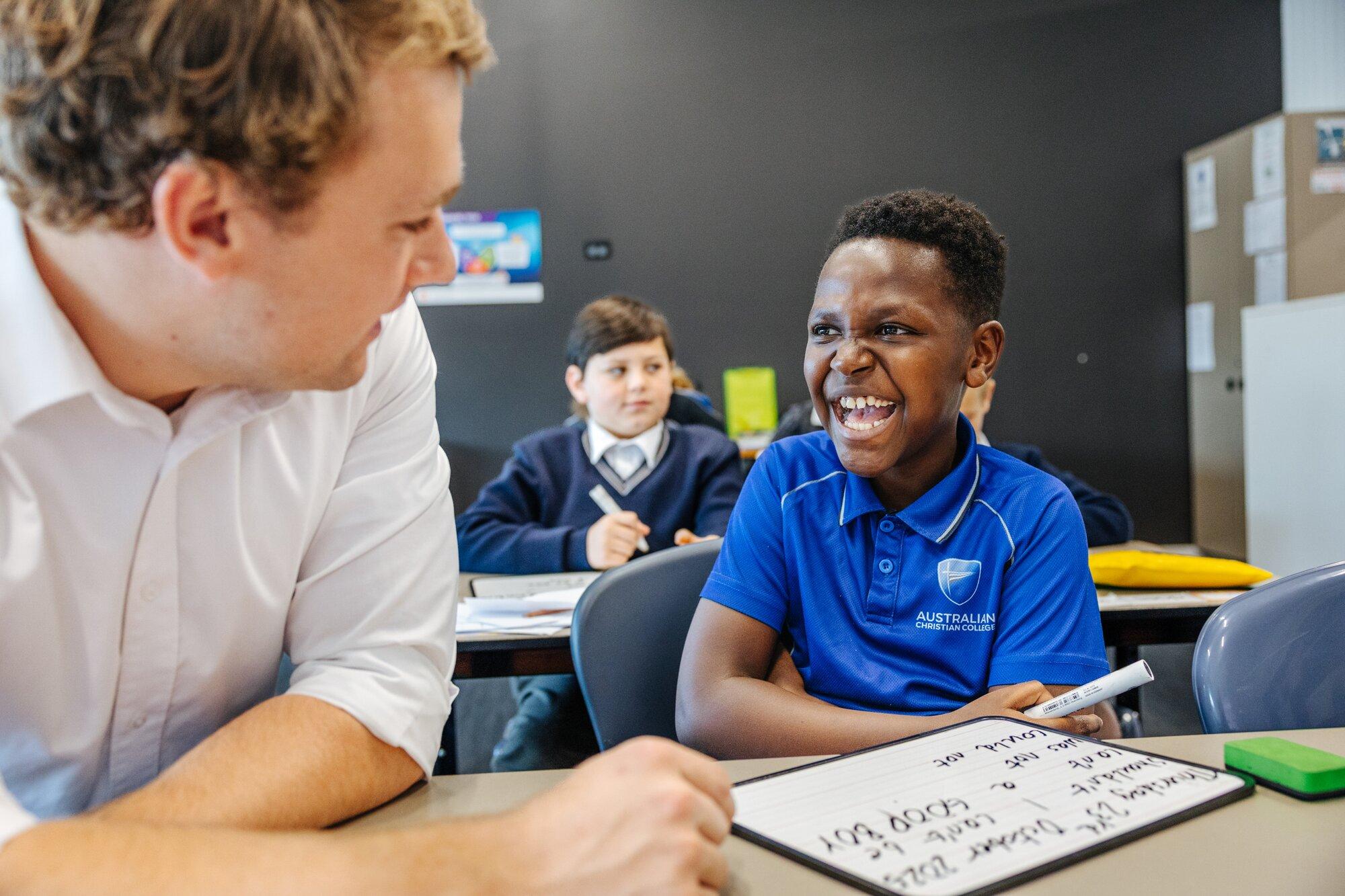 Teacher supporting a primary student with whiteboard work in class