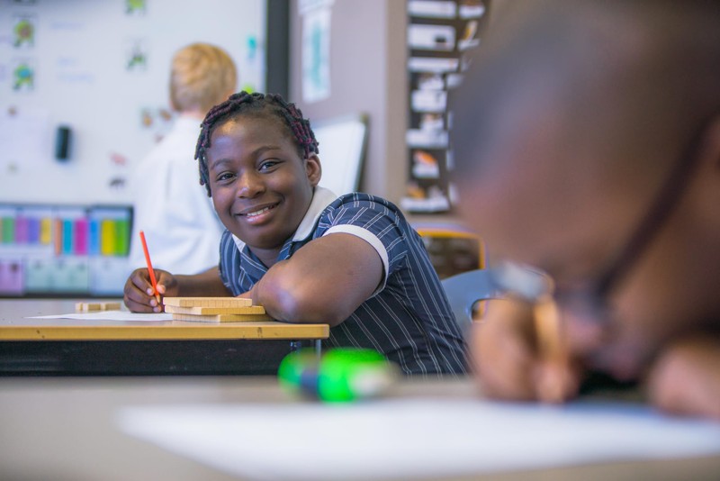 Smiling female student with hair-bow in library