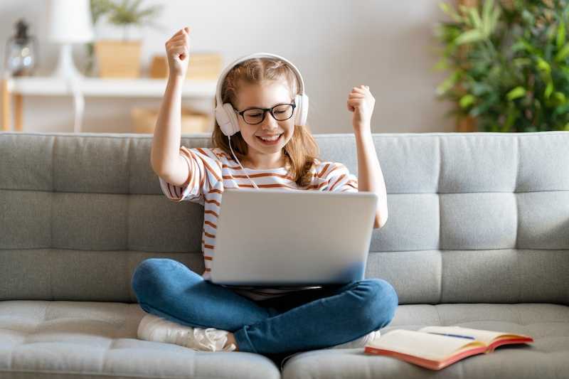 Excited Tasmanian student completing distance education lesson on laptop and celebrating