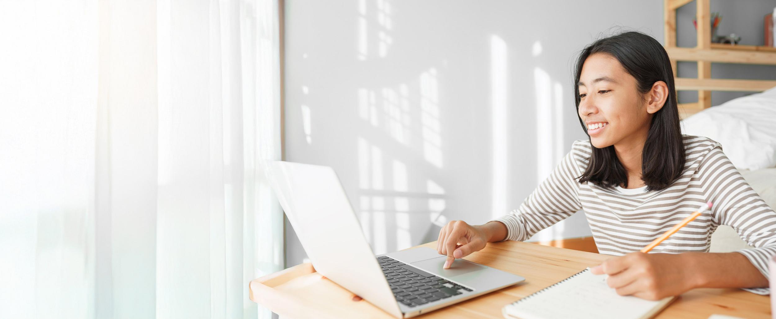 Student engaged in a home-based virtual lesson, using a laptop for distance education.