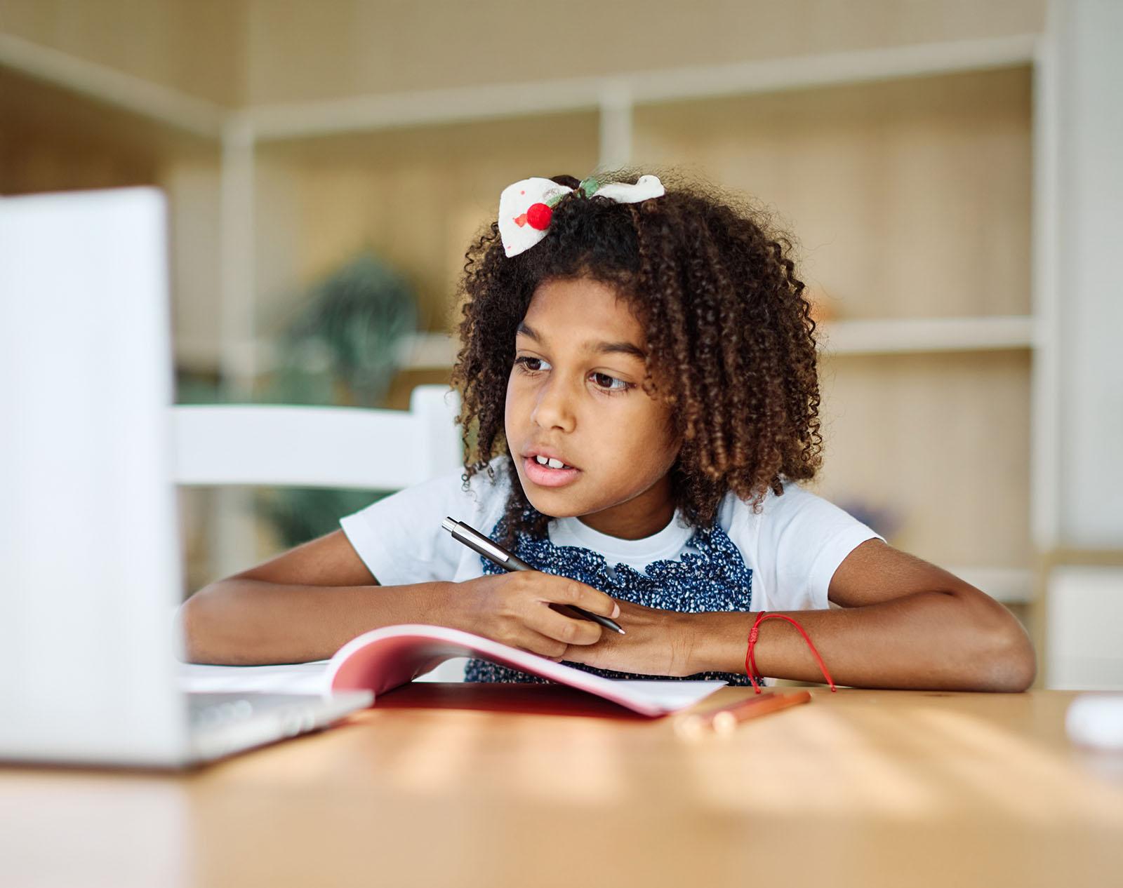 Primary student writing in a notebook at home