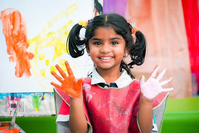SmartPlay early learning student wearing a painting smock