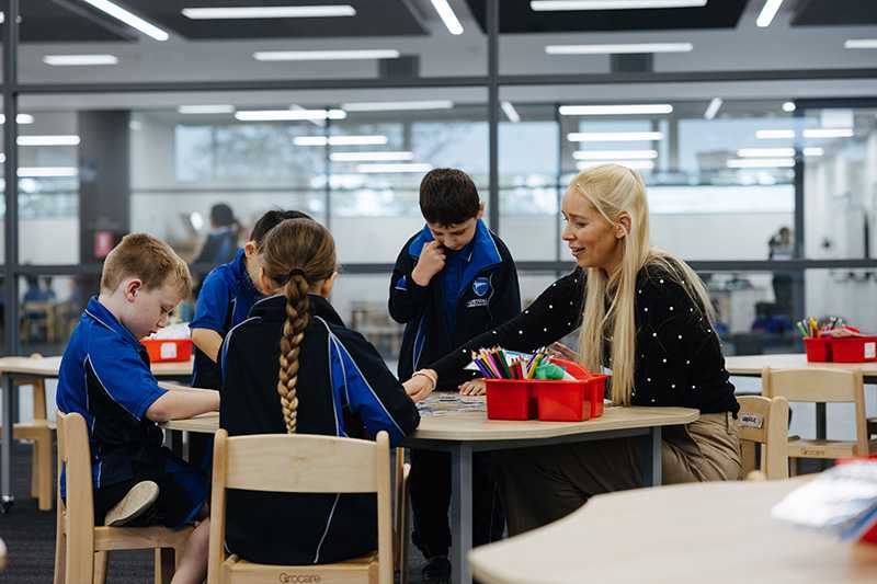 Teacher sitting at table of kindergarten childen