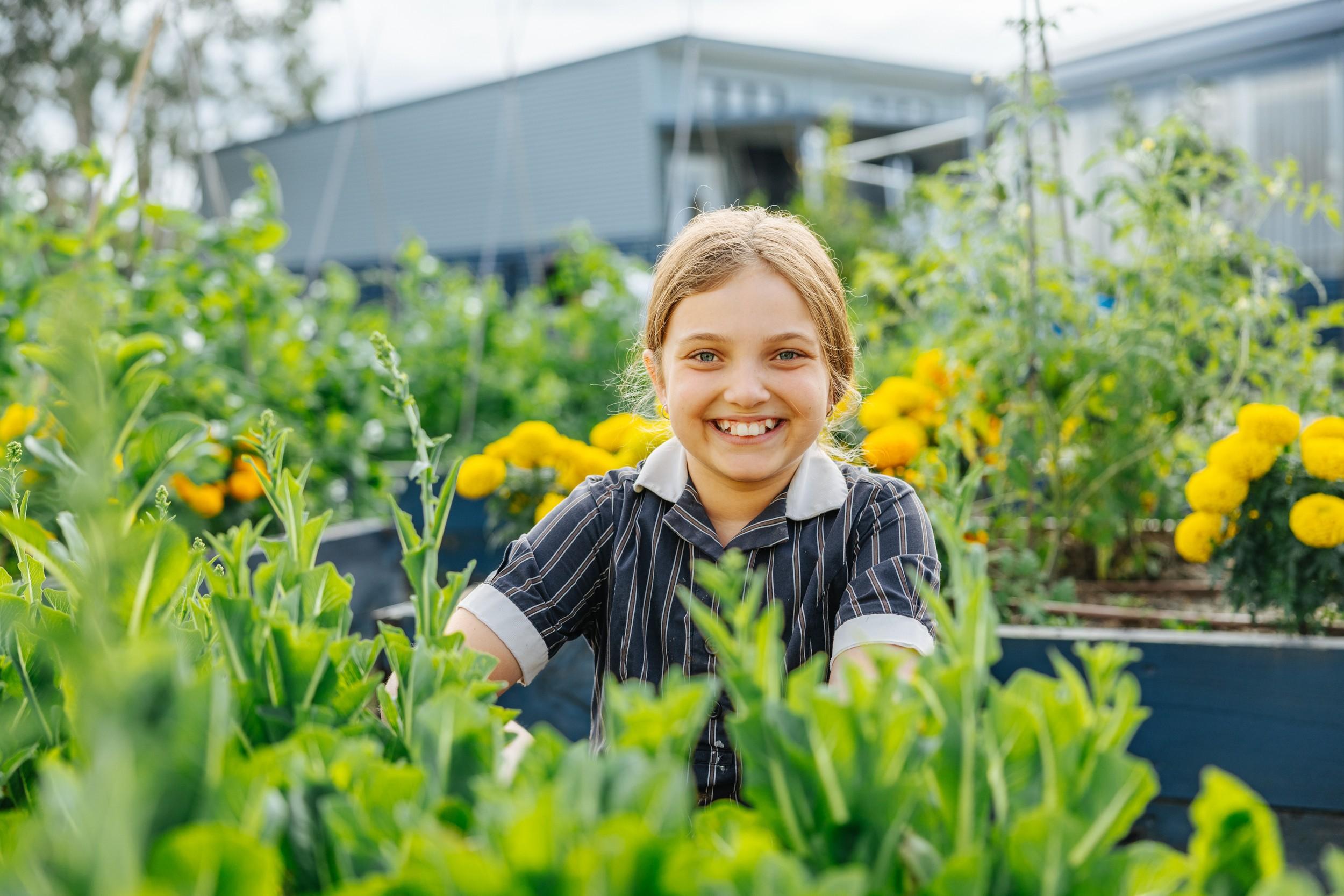 A primary student smiling in the school garden at ACC Moreton