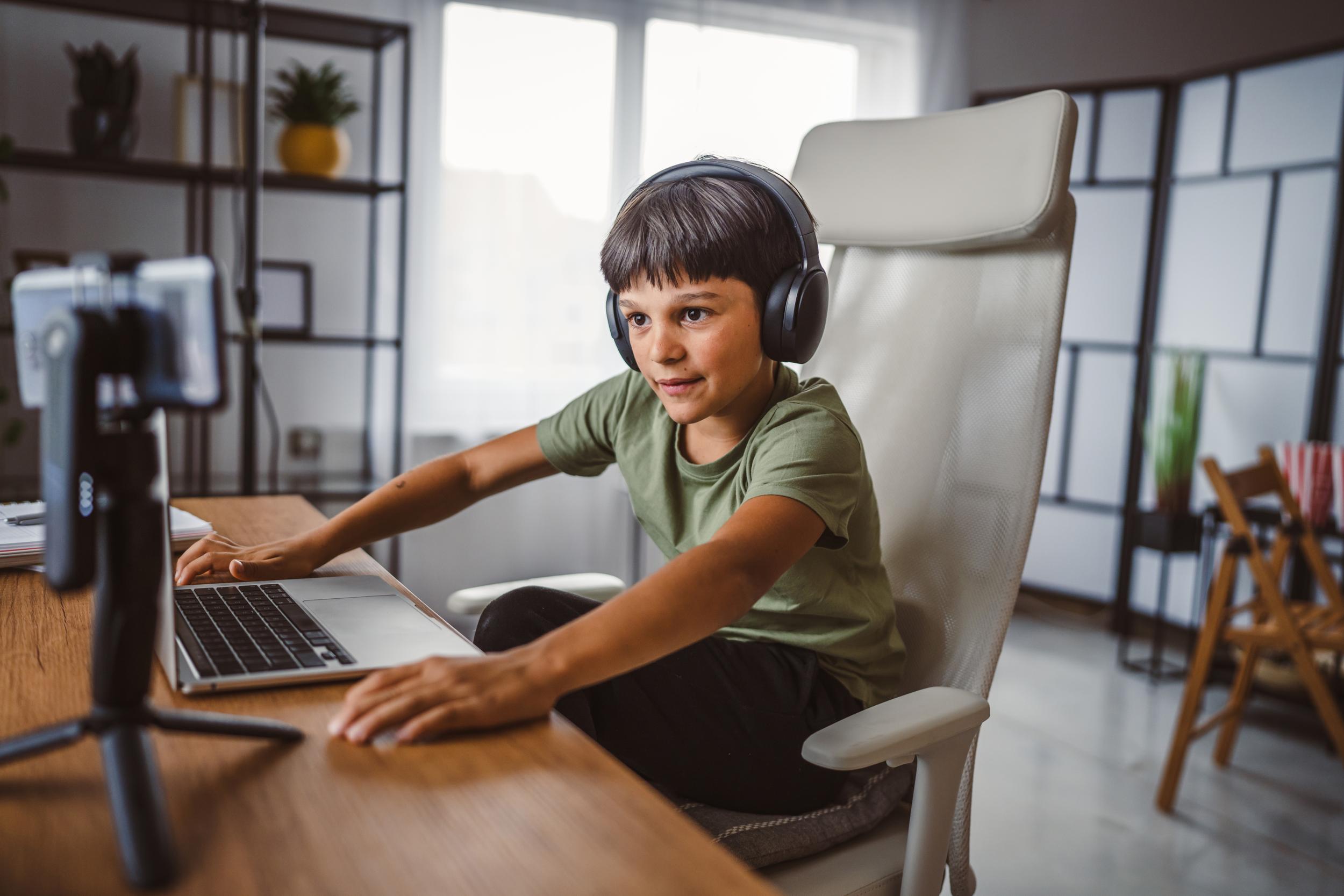 A student at ACC Moreton engages in online learning, wearing headphones and focused on a laptop