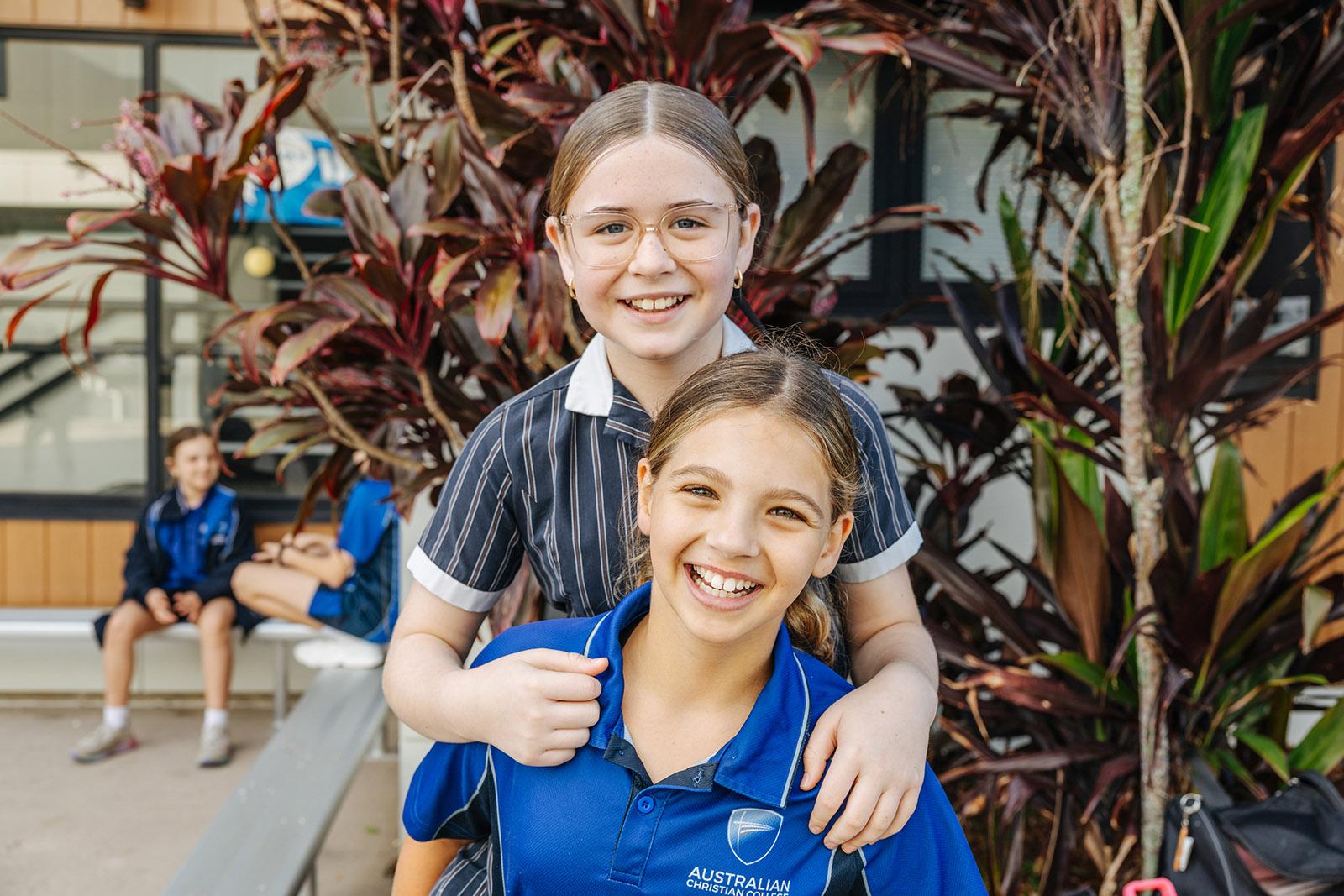 Two ACC Moreton students smiling together in a supportive school courtyard
