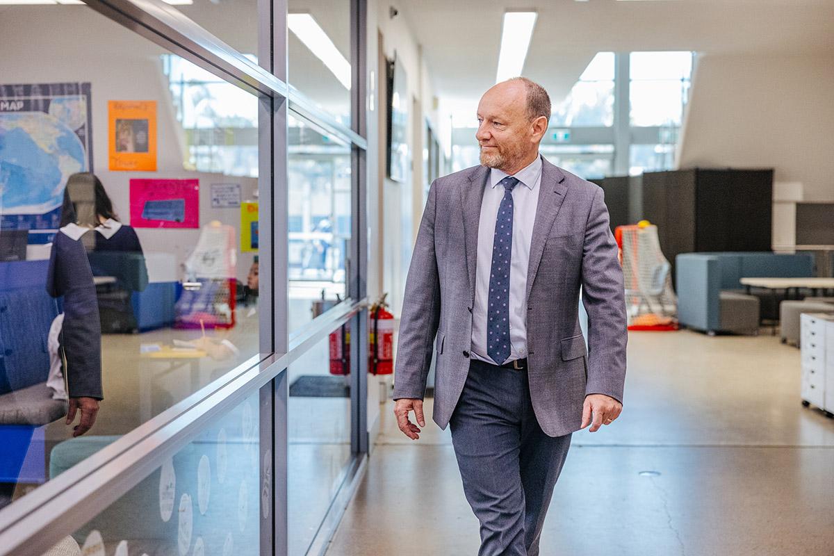 ACC Moreton principal walking through a school hallway.