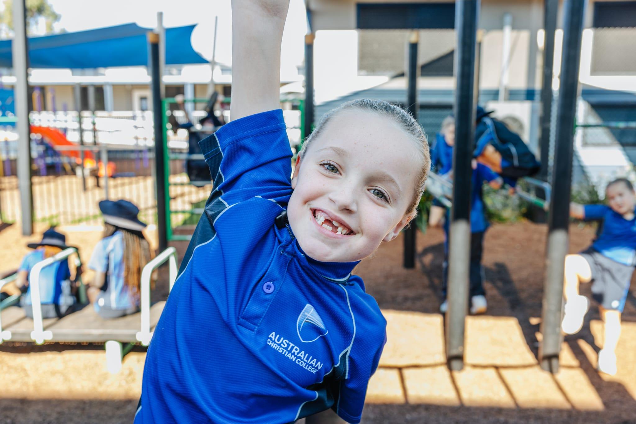 Primary student building confidence hanging off monkey bars at ACC Moreton