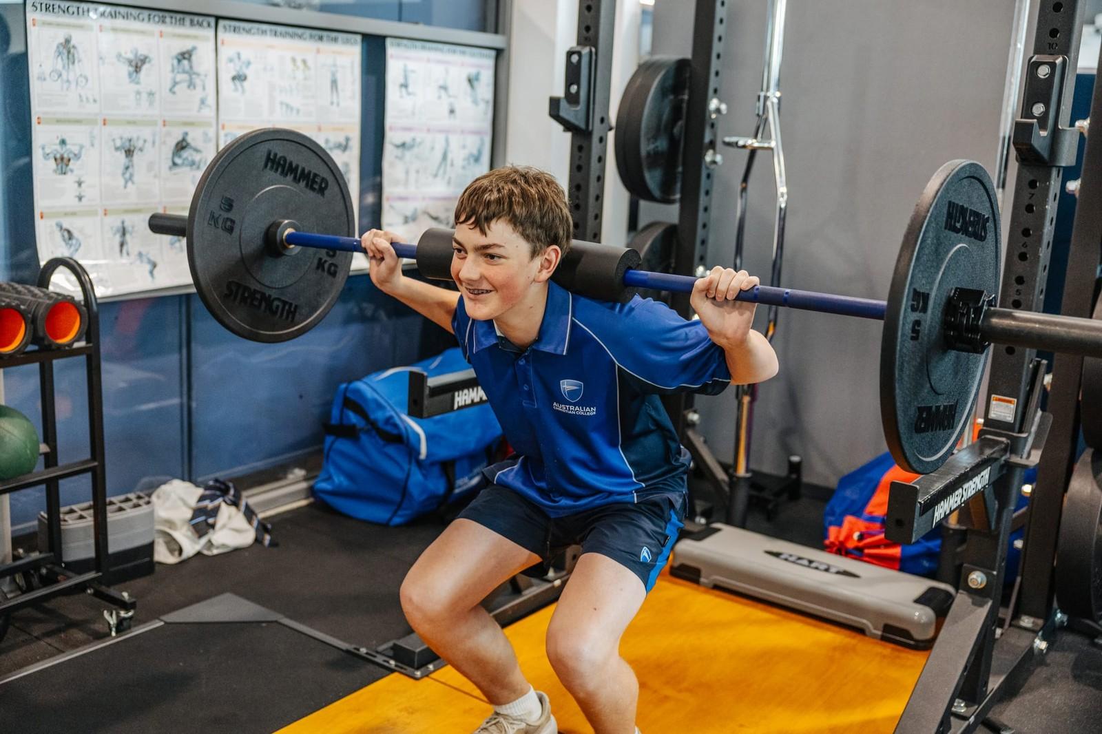 Secondary student building strength in the school gym during physical education