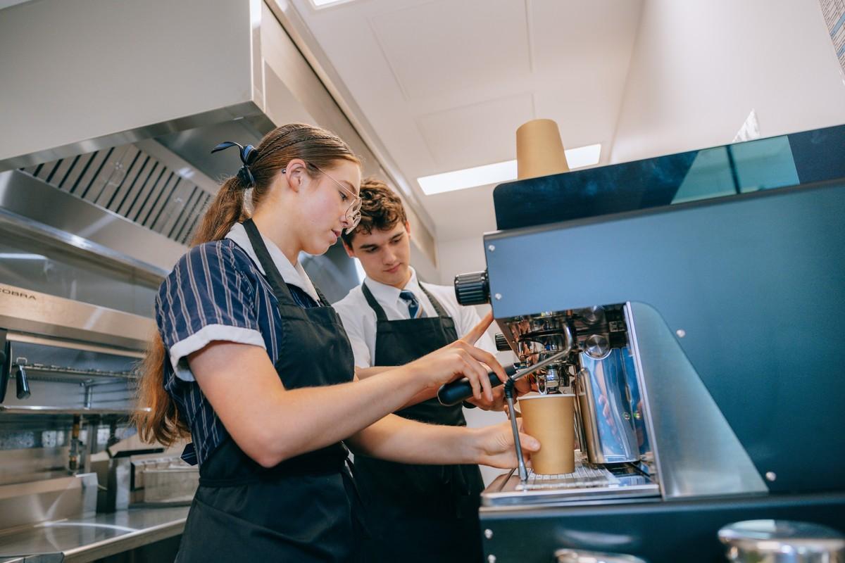 Secondary student learning food preparation with an instructor in hospitality class