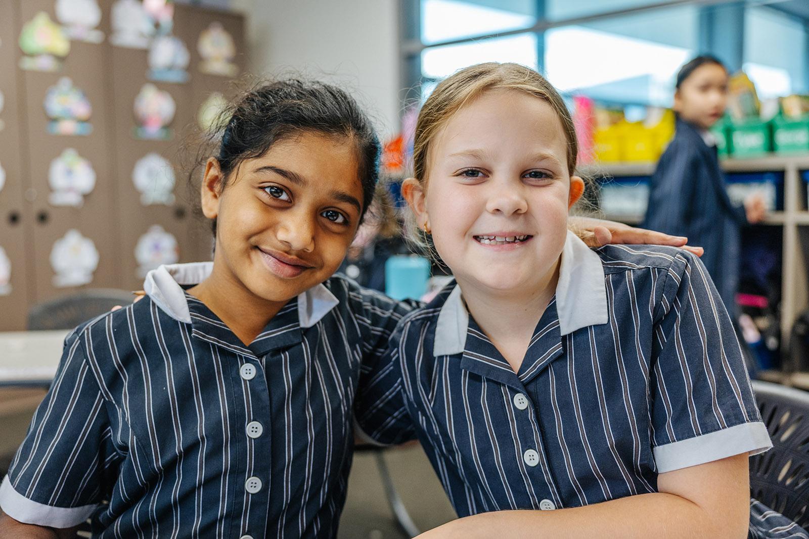 Two primary students smiling together in a classroom at ACC Moreton