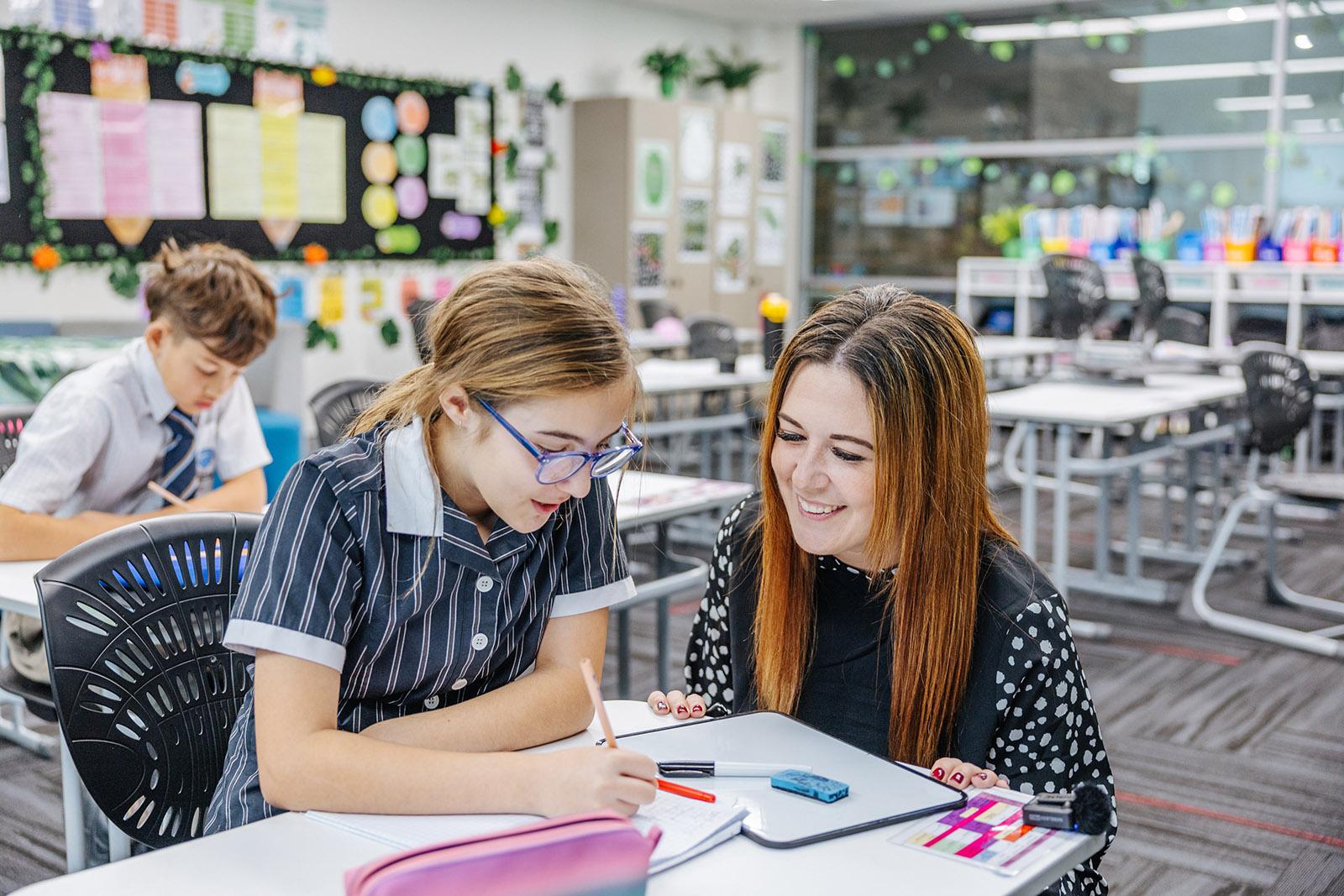 Two ACC Moreton students reading together in a primary classroom