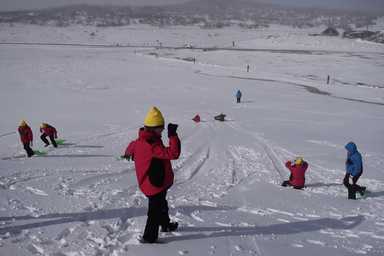 Queensland distance education students on snow trip sliding down snowy hill