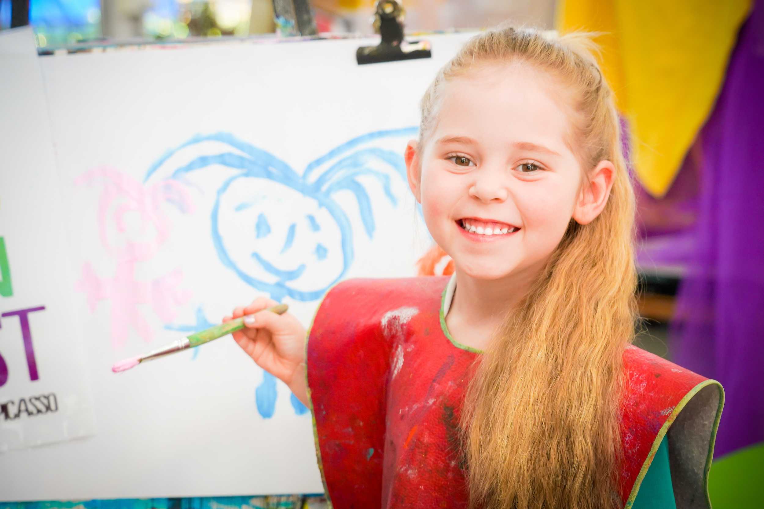SmartPlay student wearing a painting smock