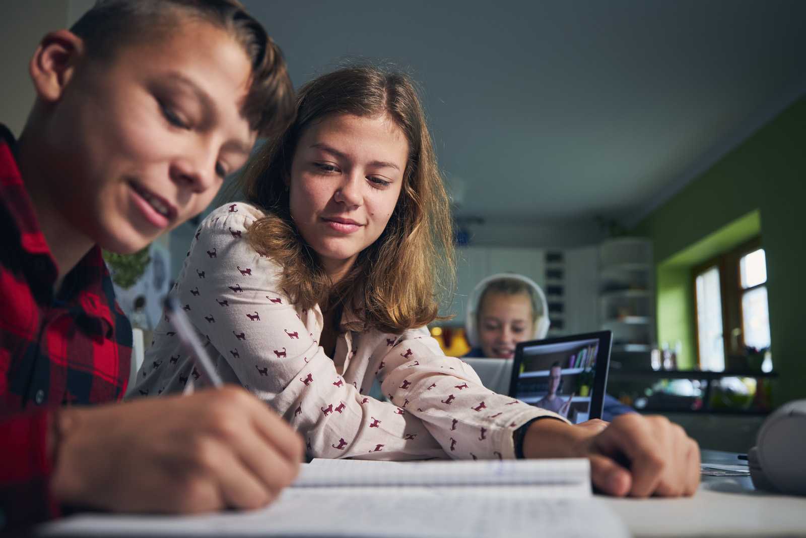 students of different ages sitting together at home completing distance education school work