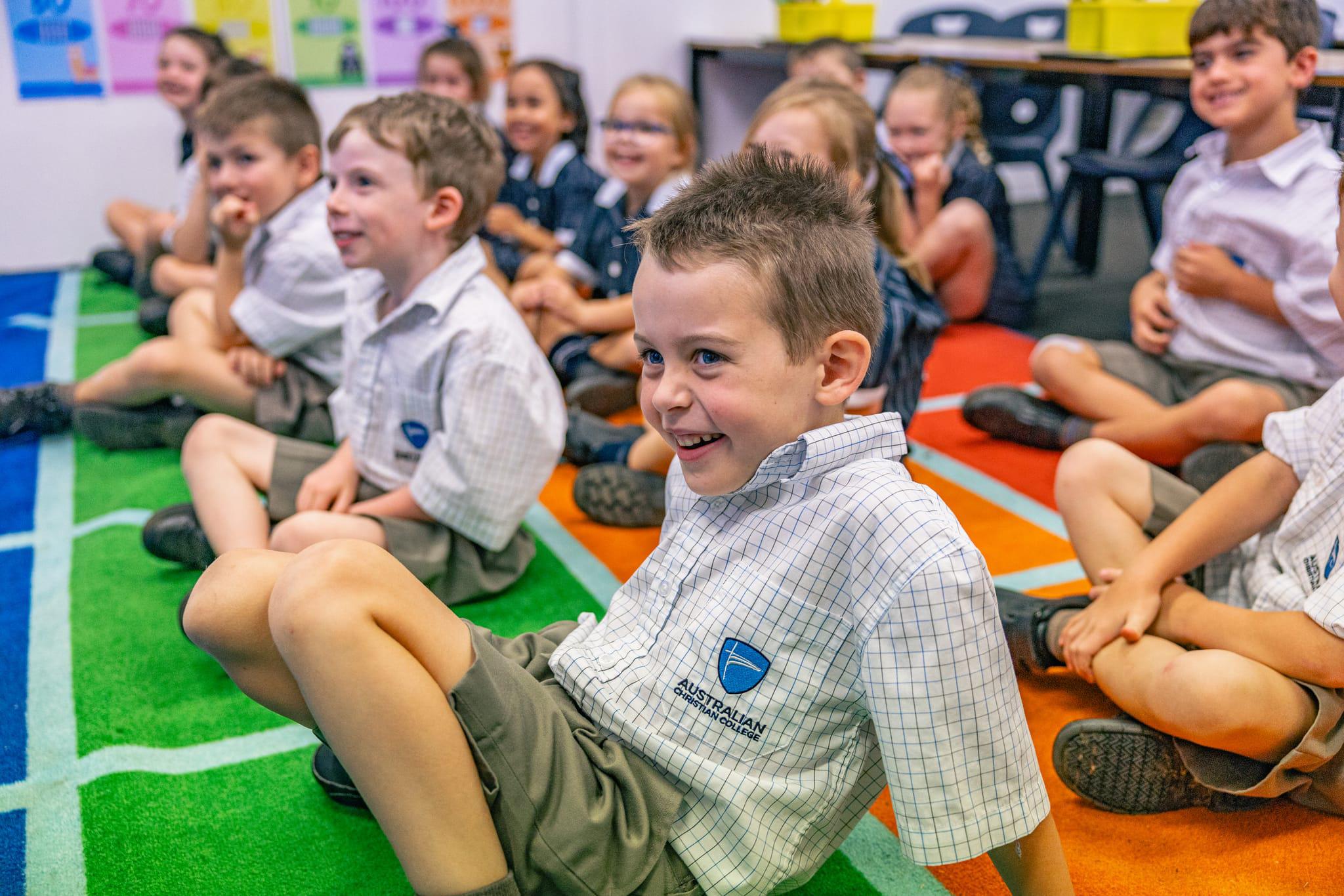 Happy junior students at ACC Singleton sitting on classroom carpet, showing joy and belonging in a caring Christian school.