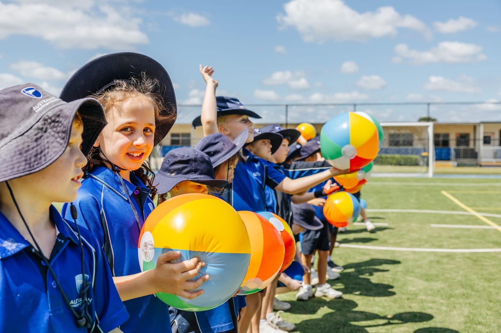 Junior students with beach balls on sports field at ACC Singleton, celebrating individuality and joyful participation