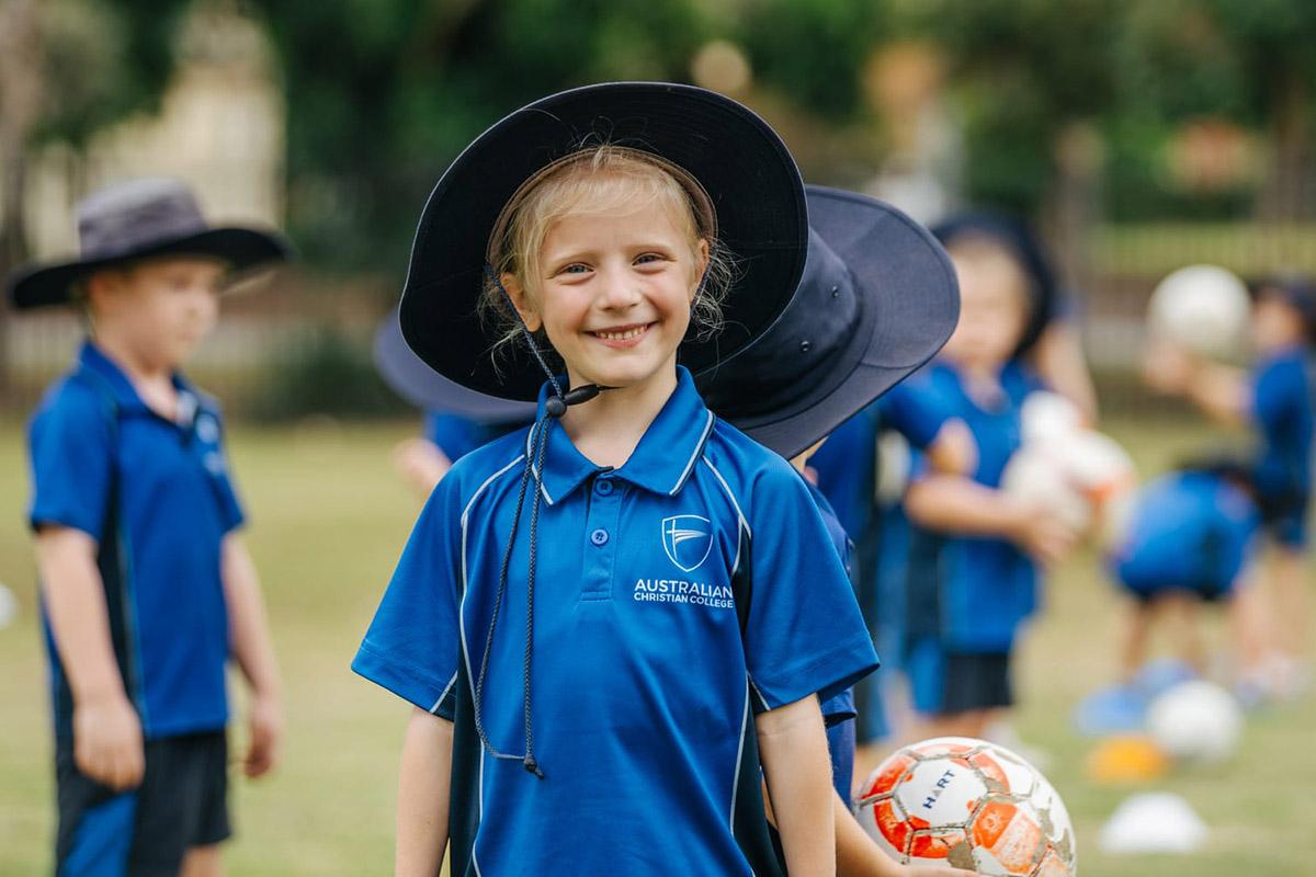 Students at ACC Singleton participate in a soccer practice, with one girl smiling in the foreground.