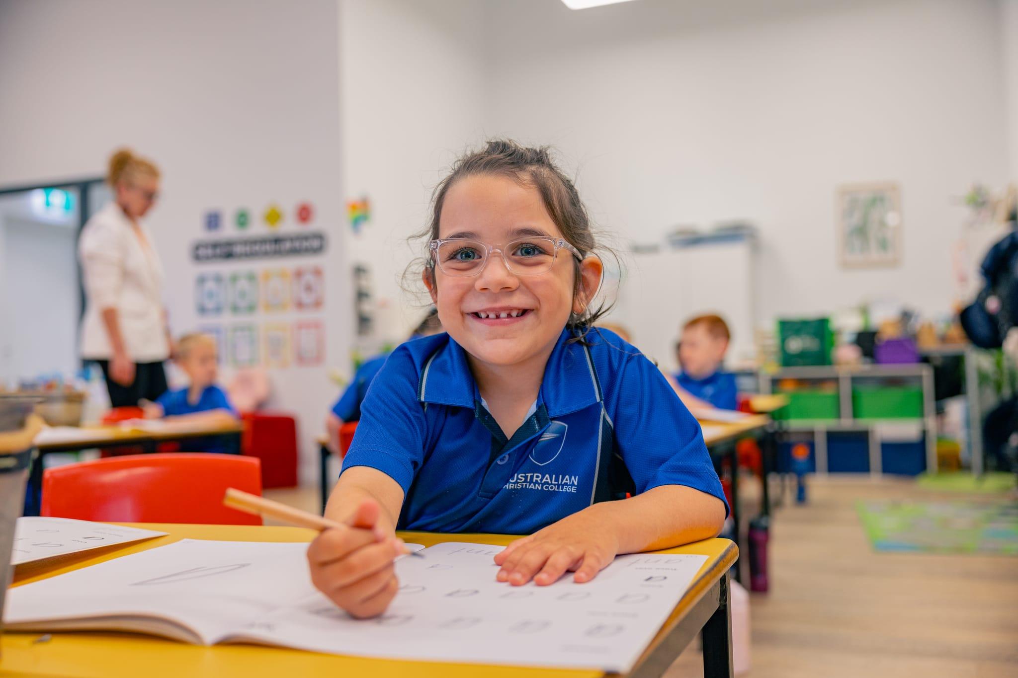 Smiling Prep student at her desk enjoying a fun early learning activity inside a bright, engaging classroom.