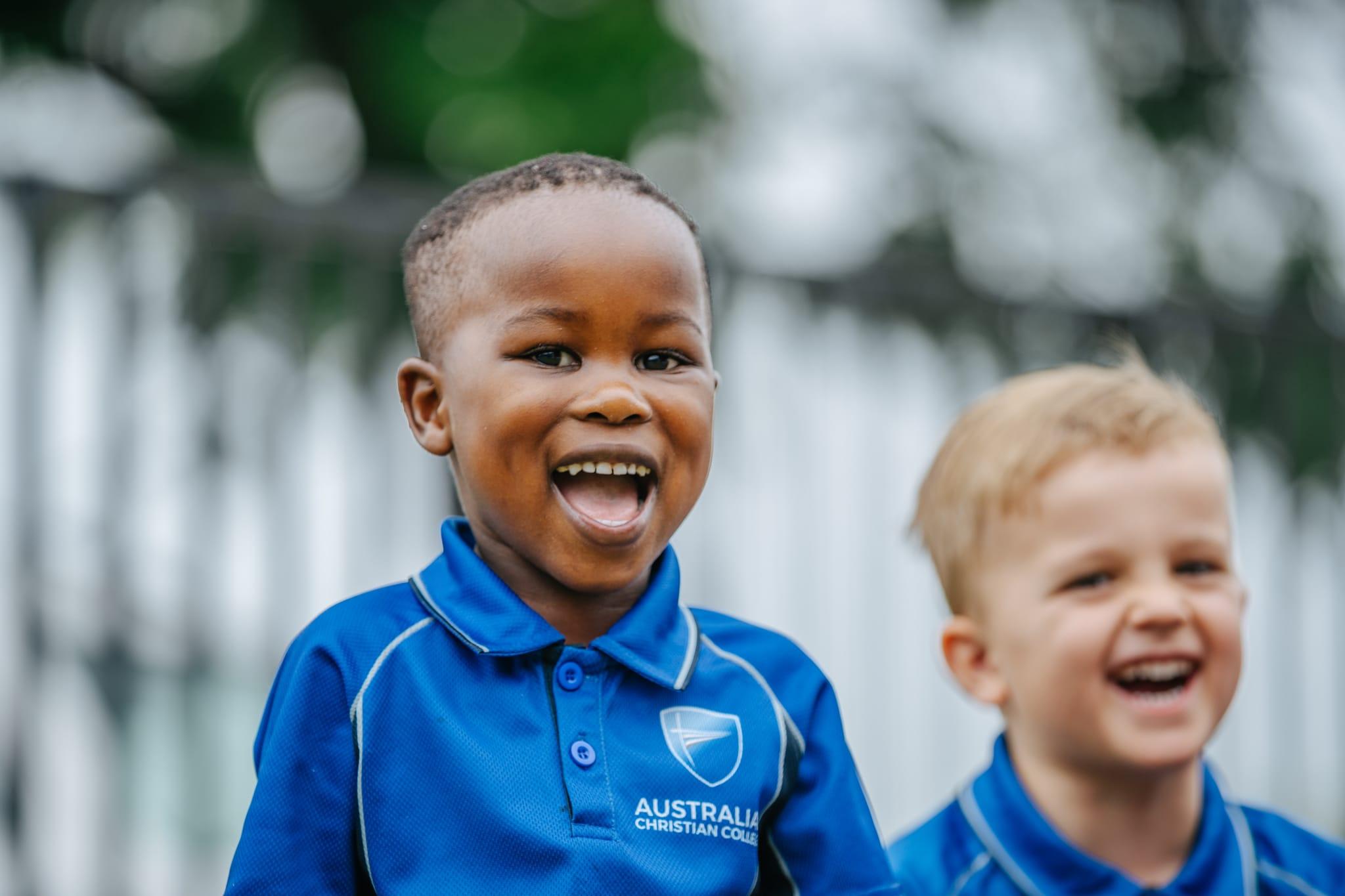 Joyful prep student smiling and playing outdoors in ACC Singleton uniform, reflecting a safe and welcoming early learning environment.