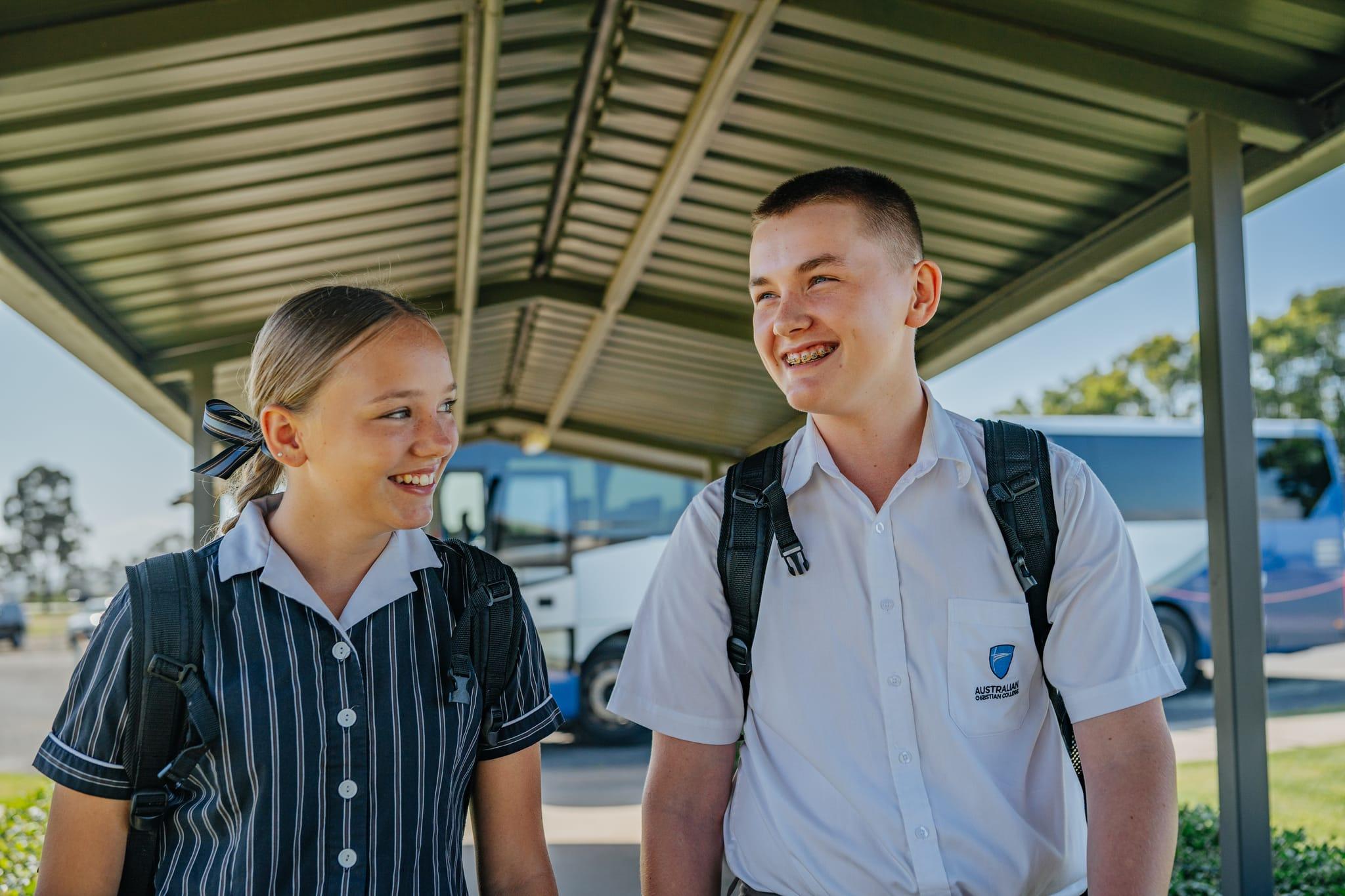 Two senior school students smiling as they arrive at school, representing confidence, connection, and a positive start to the day at ACC Singleton.