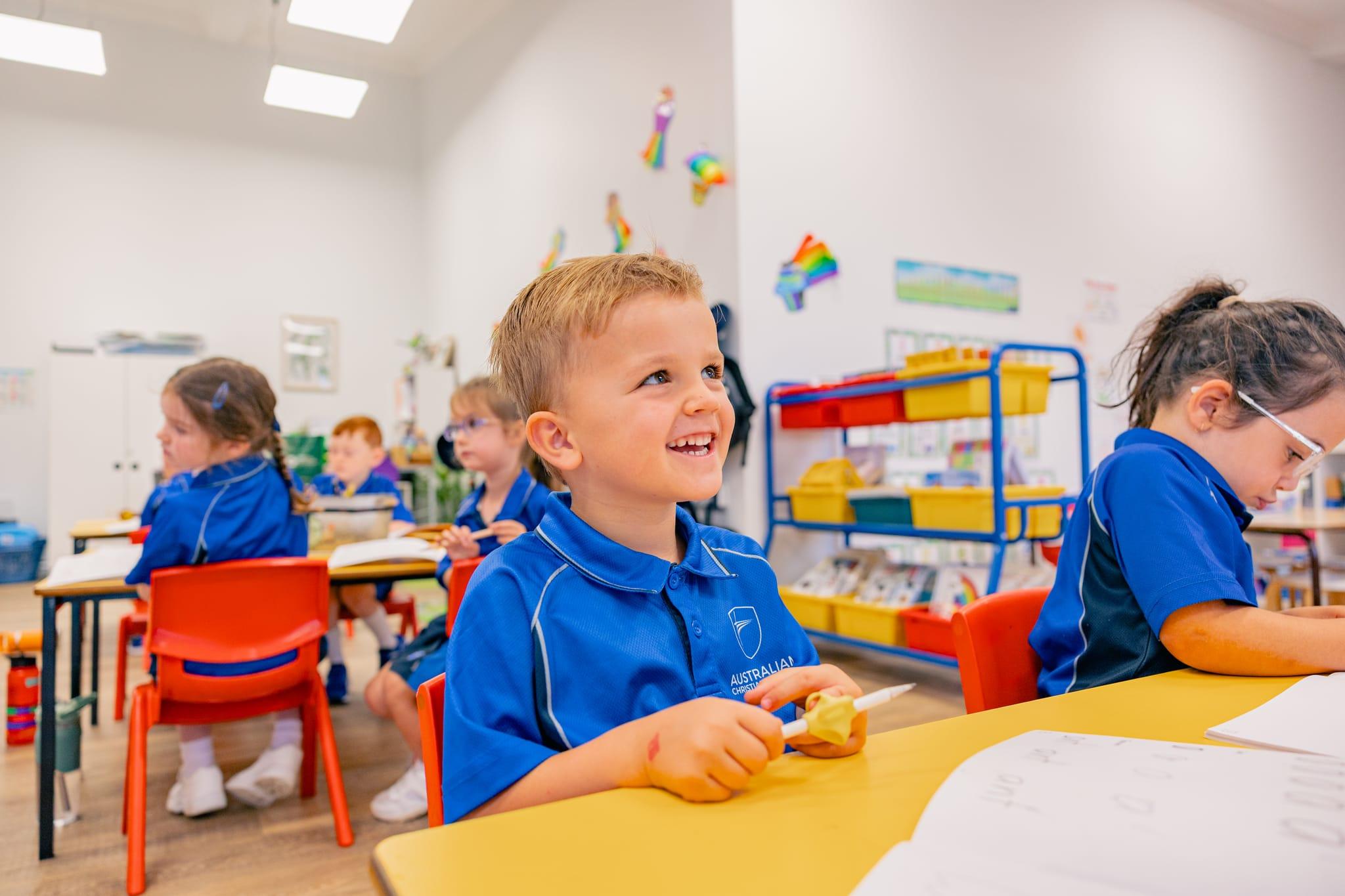 Young boy smiling during a play-based classroom activity, showing enthusiasm for early learning at ACC Singleton.
