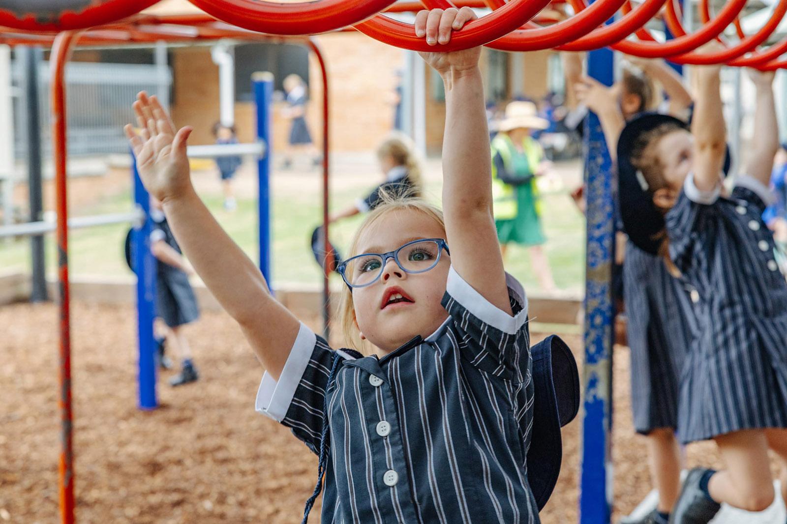 Young student on playground climbing frame at ACC Singleton, highlighting active learning in a value-focused school