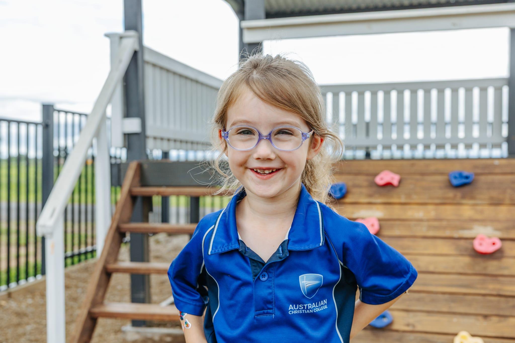 Young girl in ACC Prep uniform smiling confidently while playing outdoors on the school playground.