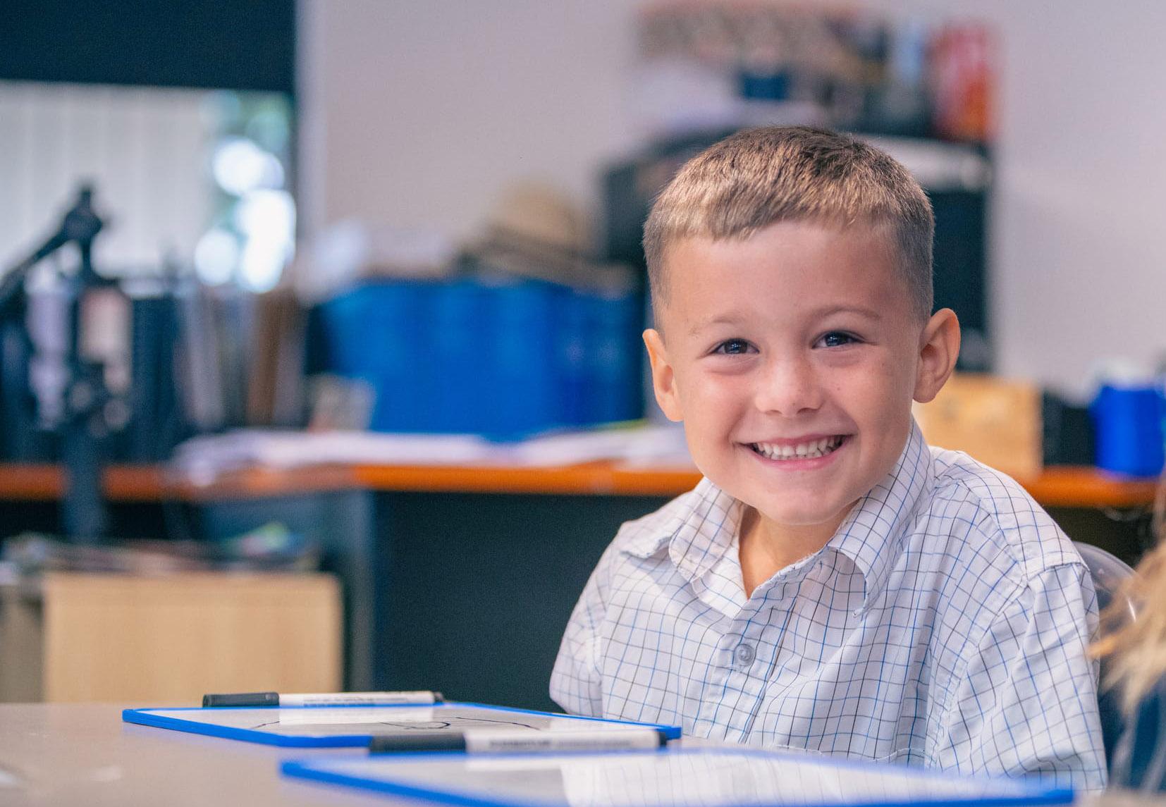 Young students smiling in class at ACC Singleton, illustrating the school’s commitment to knowing each child personally
