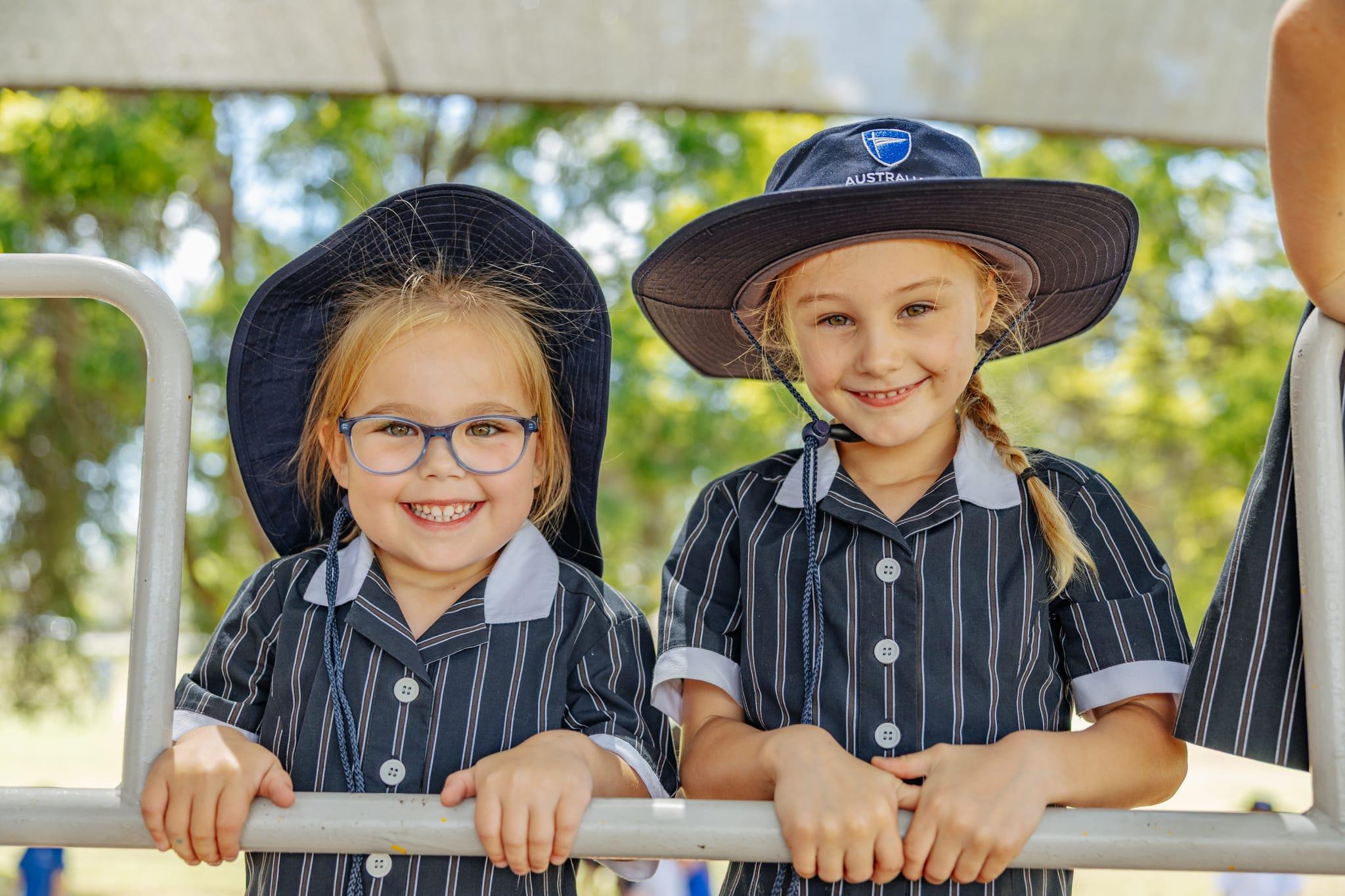 Four junior school girls sitting together under trees, smiling and chatting during recess—showcasing strong friendships and a caring Christian school community.