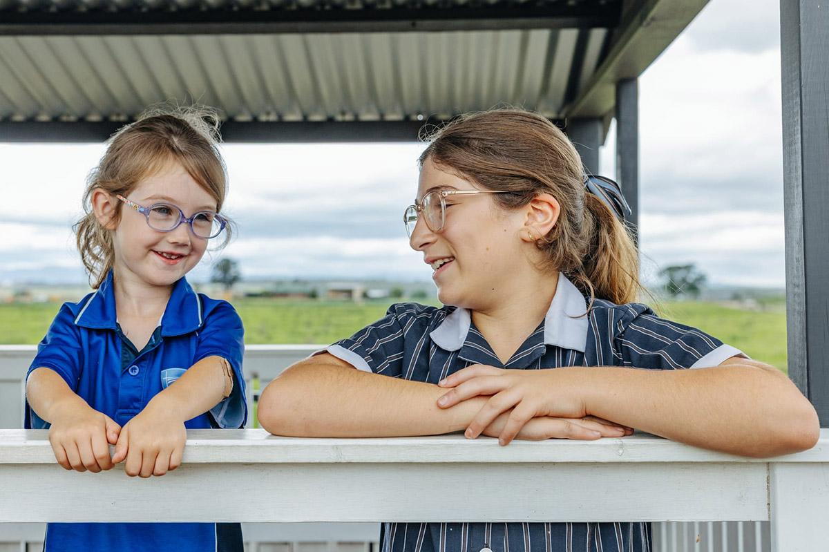 Older student chatting warmly with a younger Prep student outdoors, highlighting belonging and mentorship within the school community.