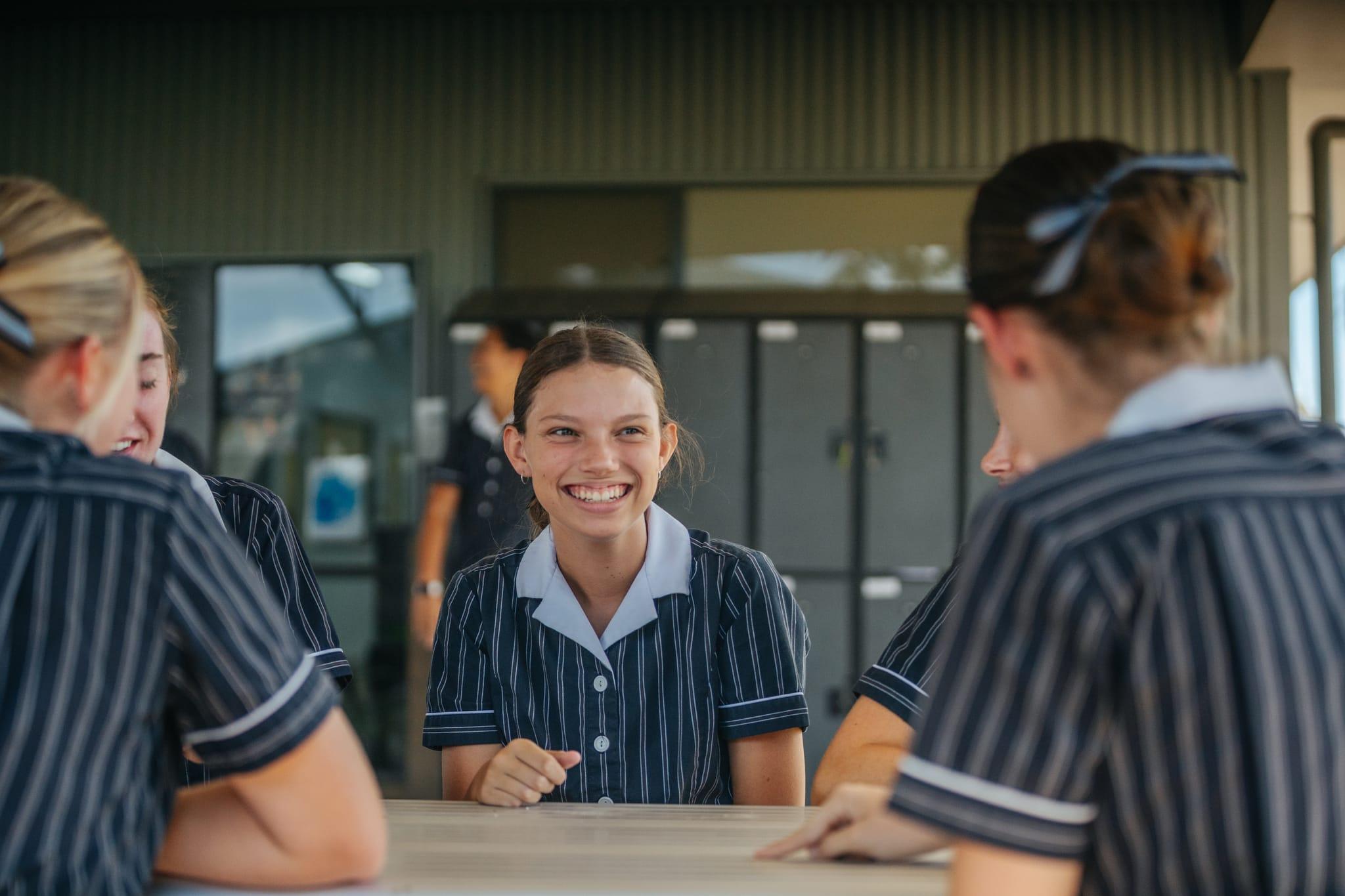 Smiling female senior student chatting with peers at school, representing the supportive and welcoming enrolment experience at ACC Singleton.