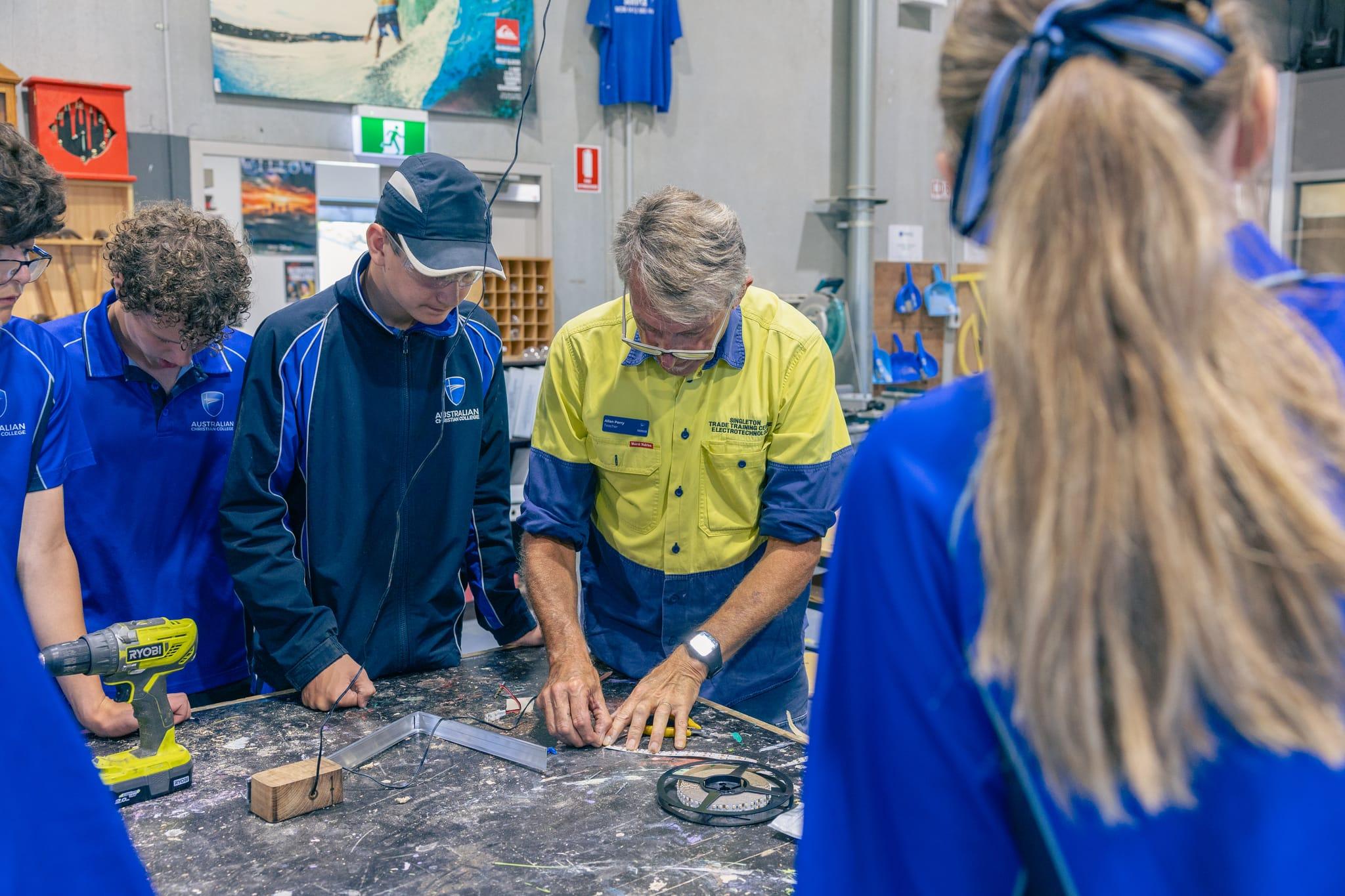 Students learning hands-on skills in the Trade Training Centre, guided by an instructor during a practical project at ACC Singleton.