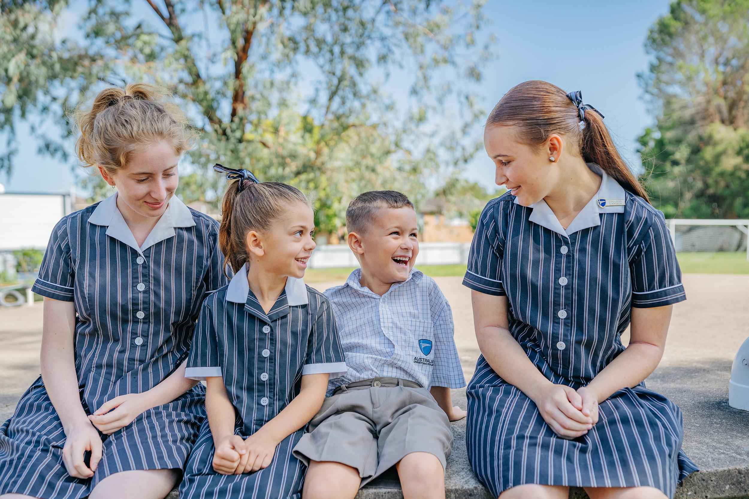 Junior and senior school students in uniform smiling together outdoors, symbolising the strong community and welcoming culture at ACC Singleton.
