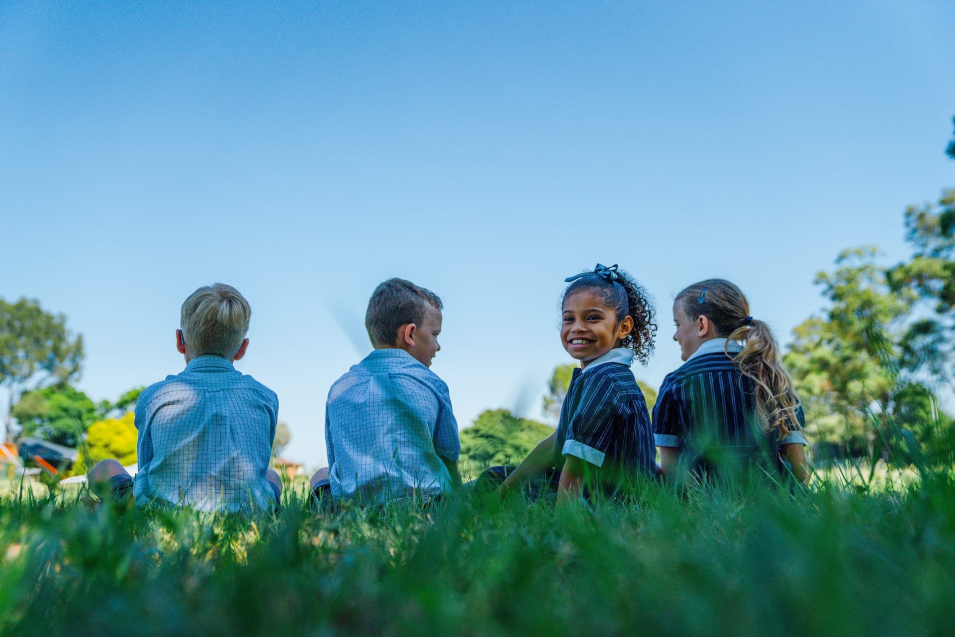 Students sitting on the field at ACC Singleton school campus