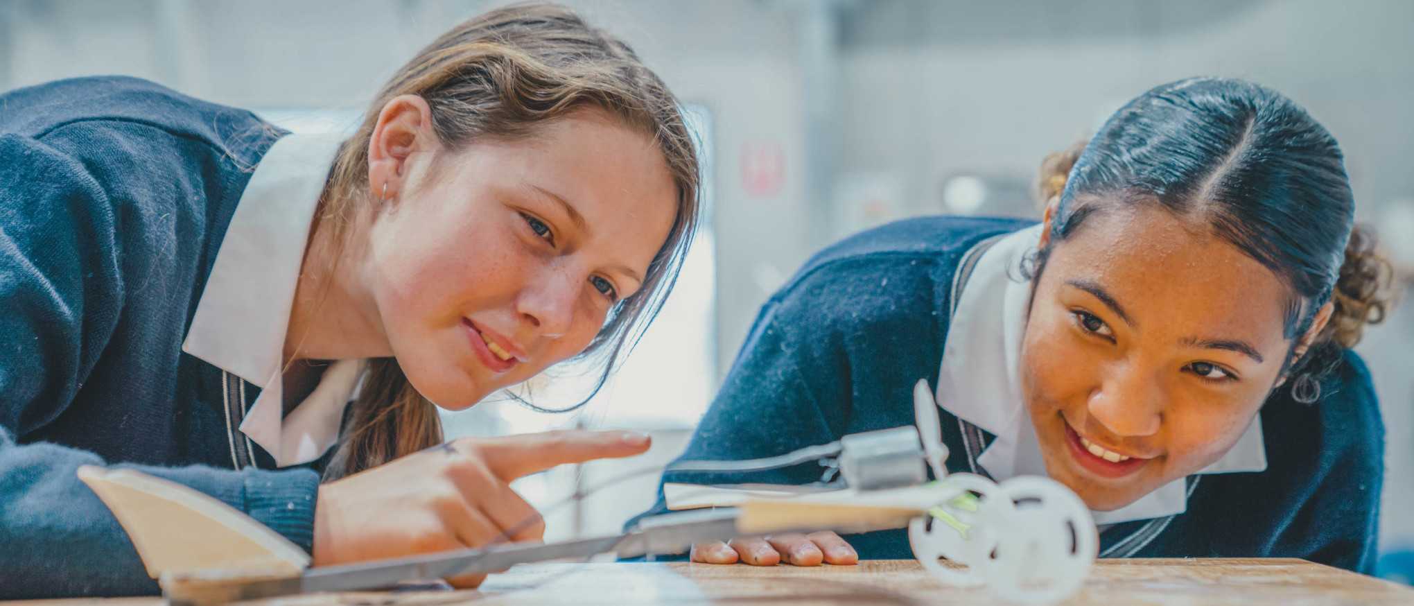 inquisitive girls looking at constructed device with propeller