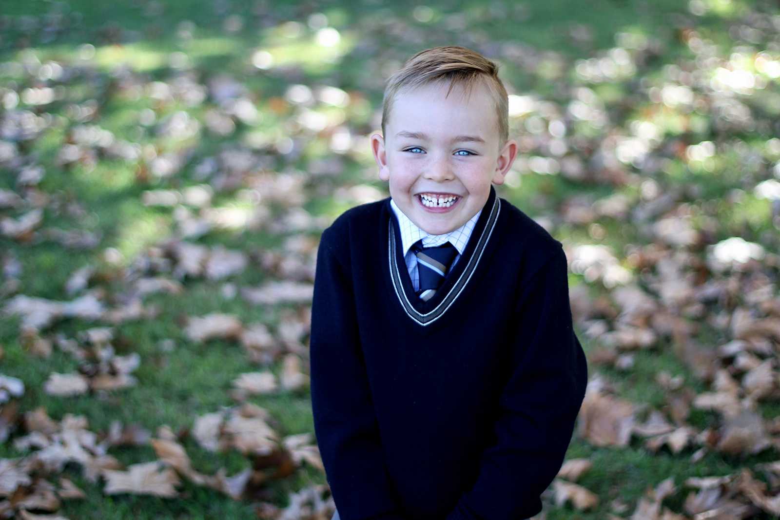 Happy Singleton primary school boy wearing school uniform jumper