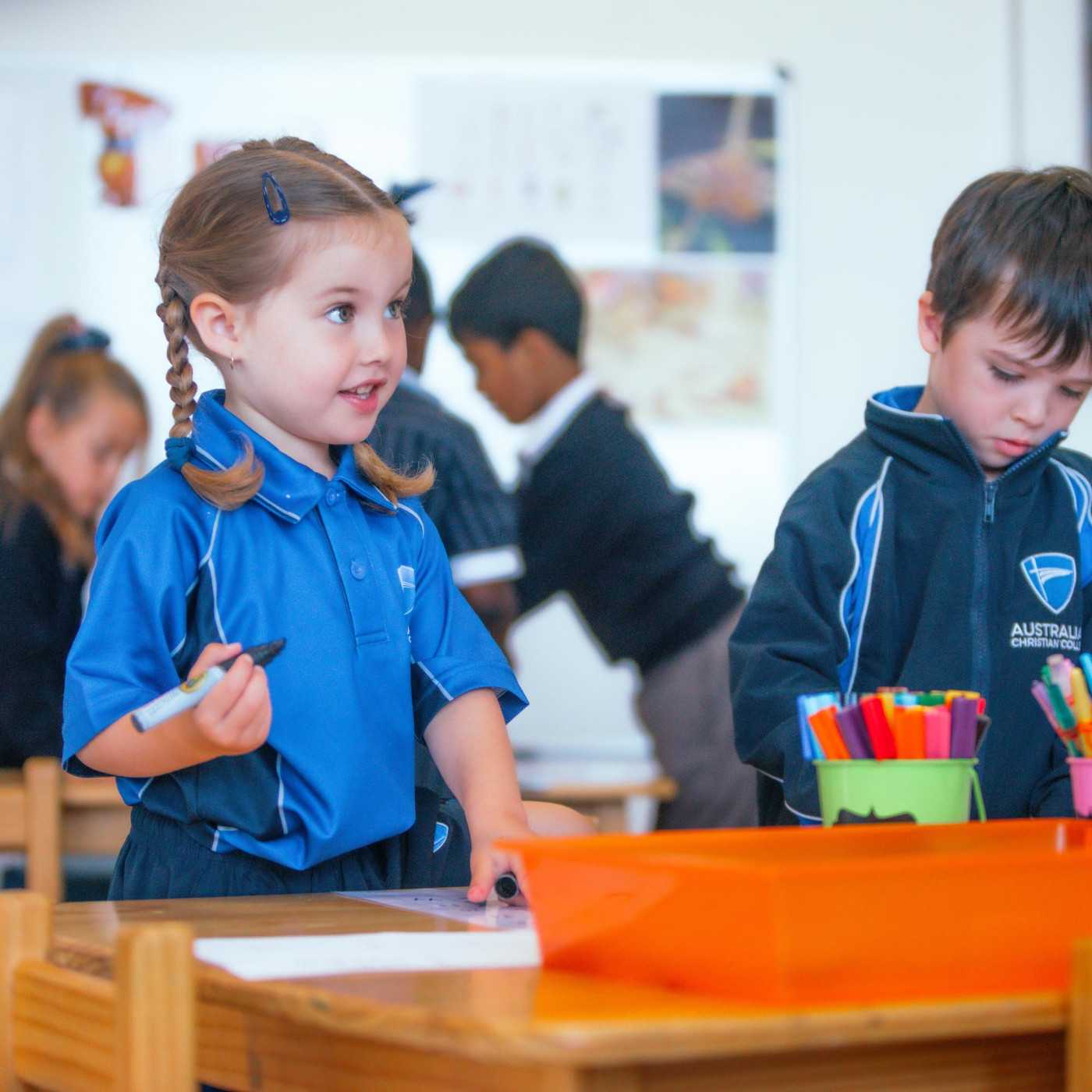 Kindergarten girl drawing and looking at teacher