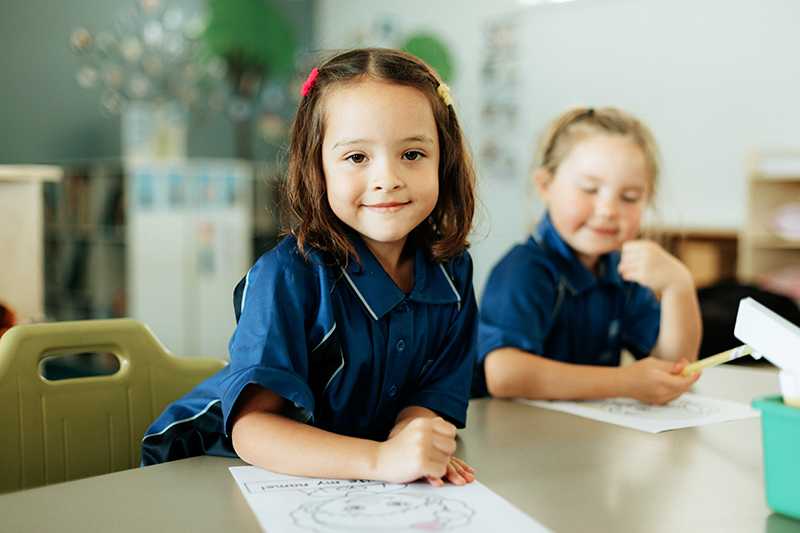 Kindergarten prep school girl at desk in school uniform polo