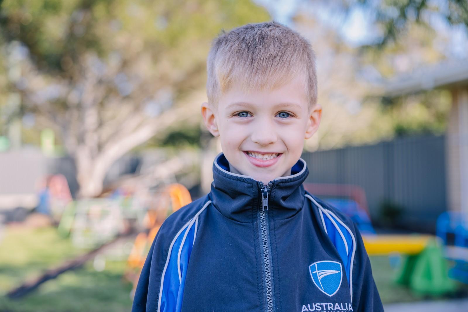 Smiling kindergarten boy in ACC tracksuit outside at the Albany school playground