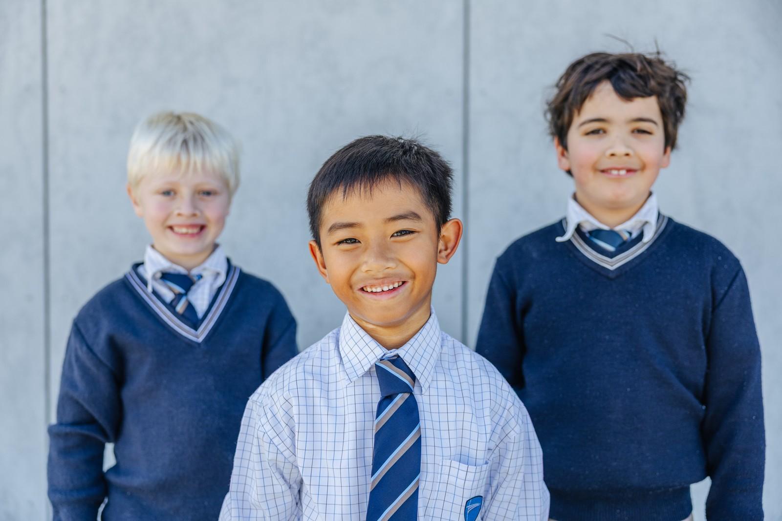 Three smiling primary school boys in uniform at an Albany Christian school