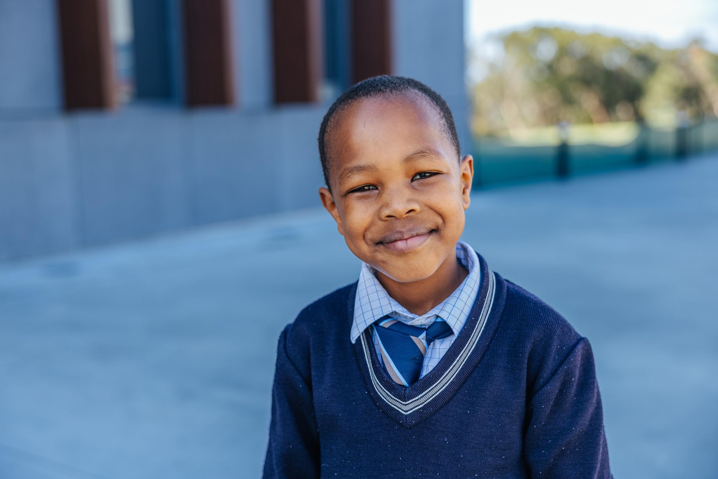 Smiling primary school boy in ACC Southlands uniform on campus